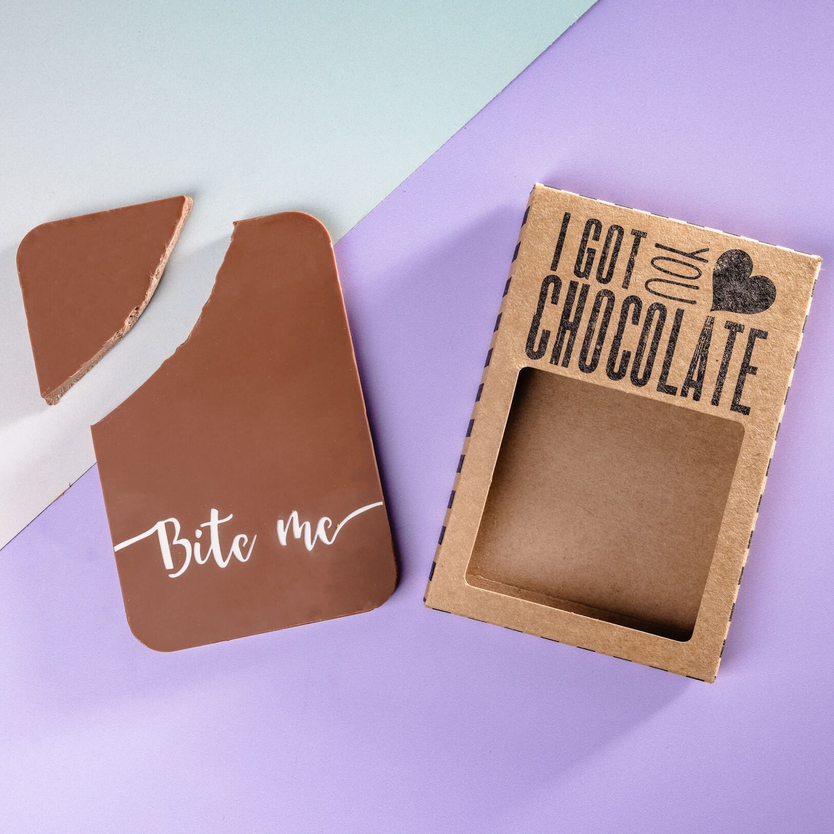 Bite Me Gift - Flat lay of a bitten “Bite me” chocolate bar next to its open kraft box packaging that reads “I got you chocolate”.