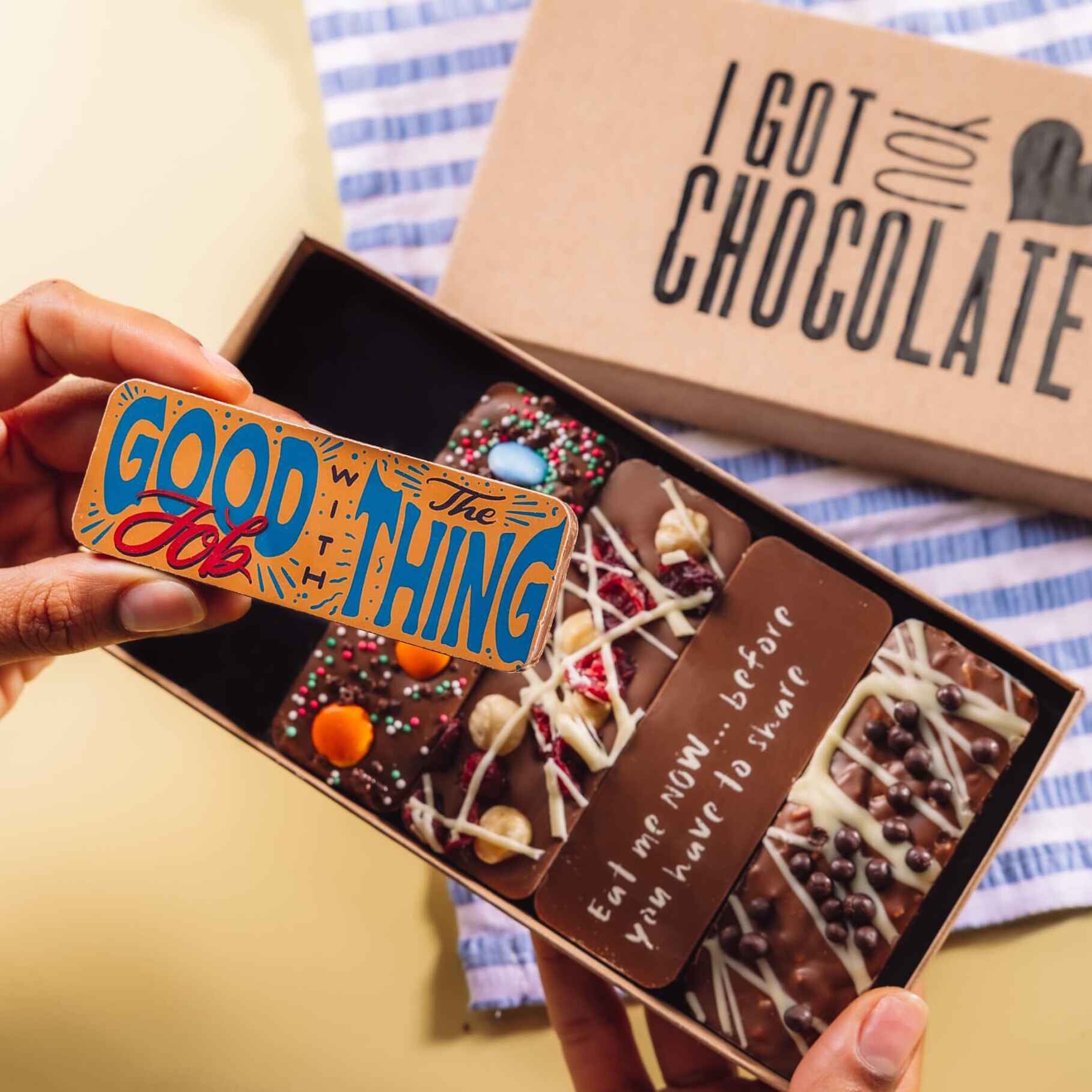 Hand holding up a chocolate bar with a colourful design reading “Good job with the thing” - part of a handmade chocolate selection box in “I got you chocolate” gift packaging – a quirky and delicious option for proud of you gifts.