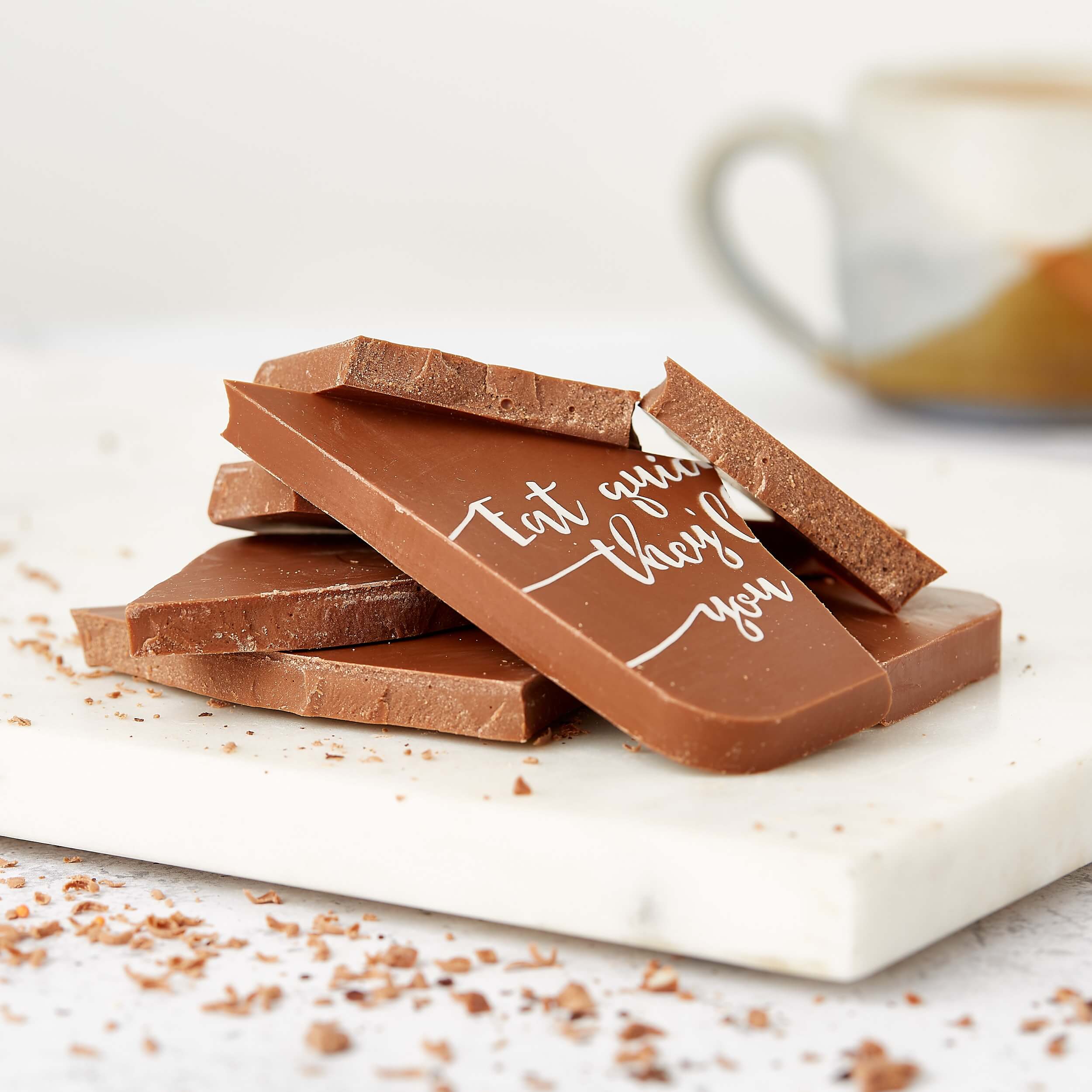 Chocolate Delivery - Stack of broken chocolate pieces showing the cheeky “Eat quick or they’ll make you share” message.