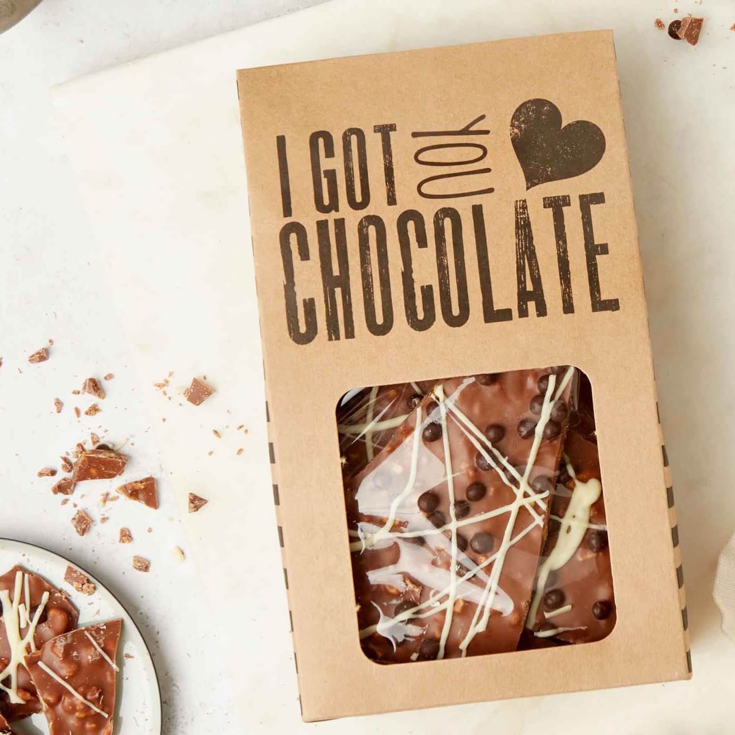 A box of loaded chocolate shards with visible honeycomb, crispy chocolate balls, and white chocolate drizzle, packaged in Bagstock & Bumble’s “I got you chocolate” gift box.