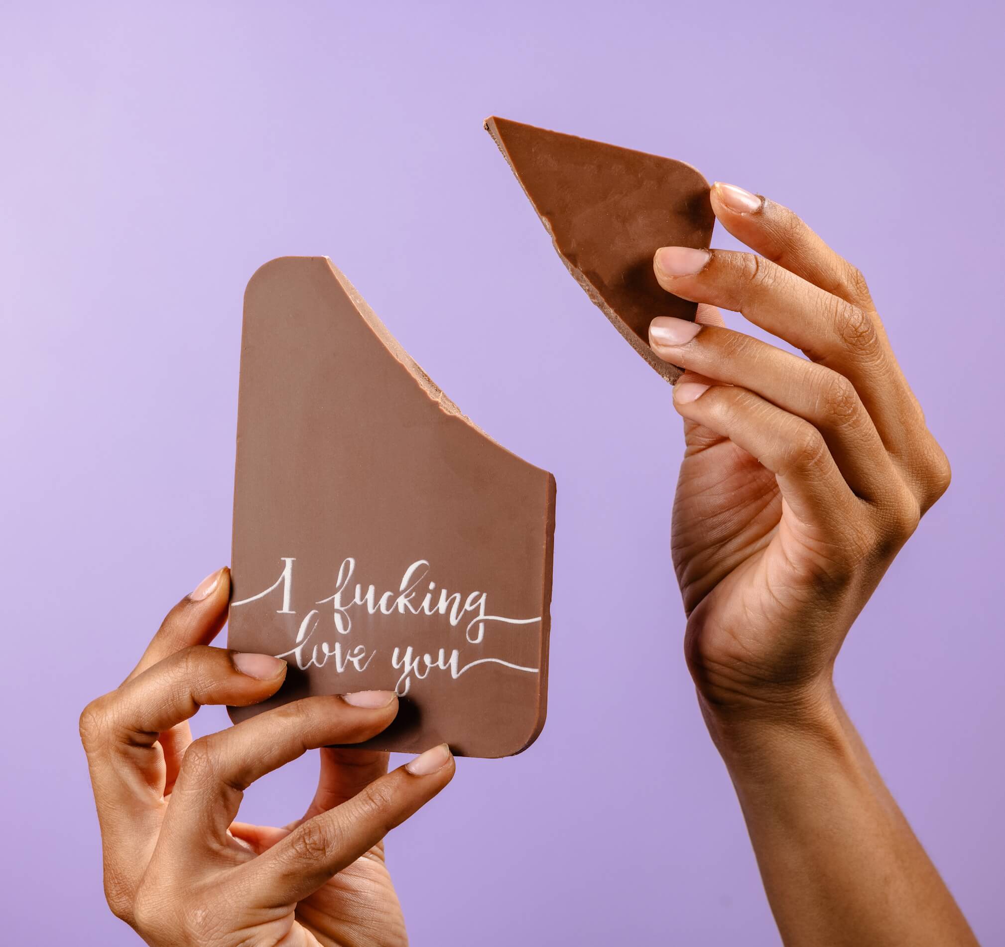 Funny chocolate gift for him – A bold chocolate bar with the message ‘I fucking love you’, made from chunky Belgian milk chocolate and shown broken in two by hand.