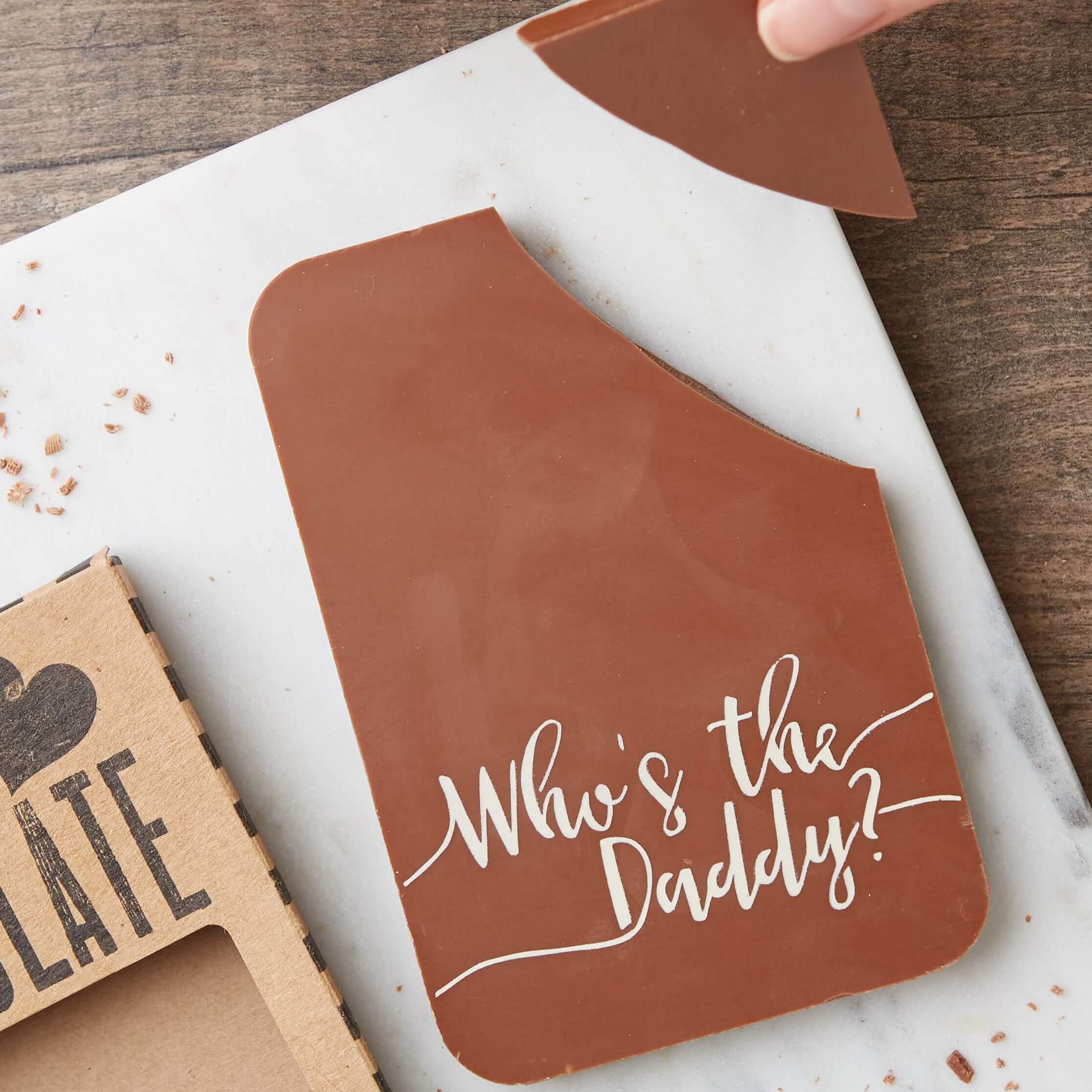 A solid Belgian chocolate bar decorated with a ‘Who’s the Daddy?’ slogan. Shown with a piece being broken off and the packaging nearby. Ideal for Father’s Day, birthdays or just because.