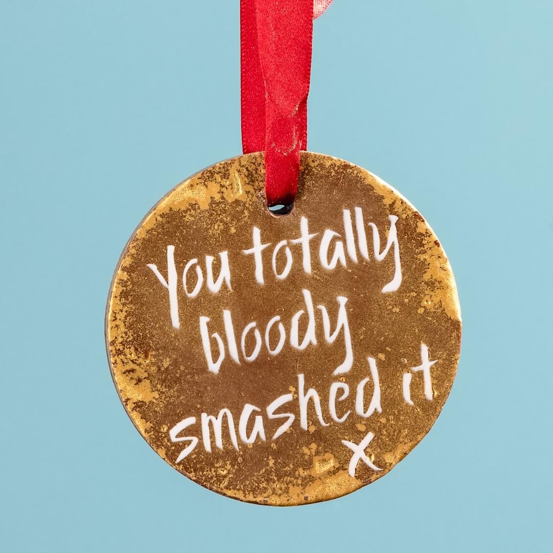 A gold chocolate medal hanging on a red ribbon and decorated with the message "You totally bloody smashed it". A scrumptious marathon gift for the runner who really deserves it.