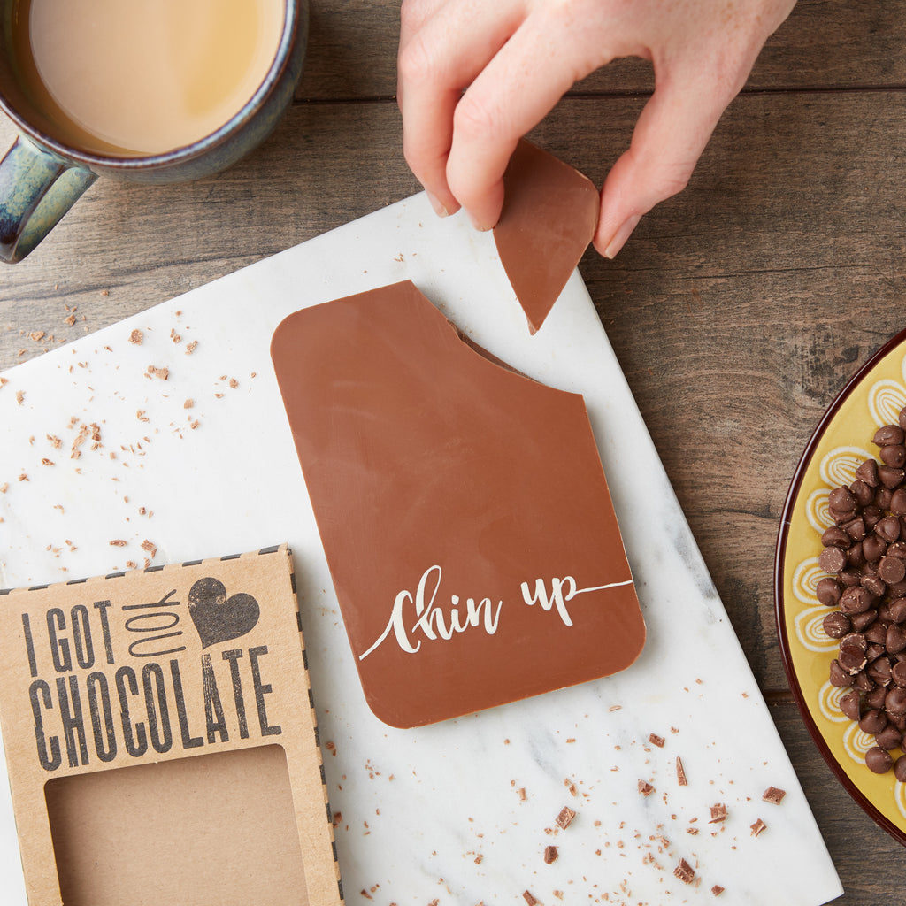 Flat lay shot of a Belgian milk chocolate bar decorated with a 'Chin up' message in coloured cocoa butter