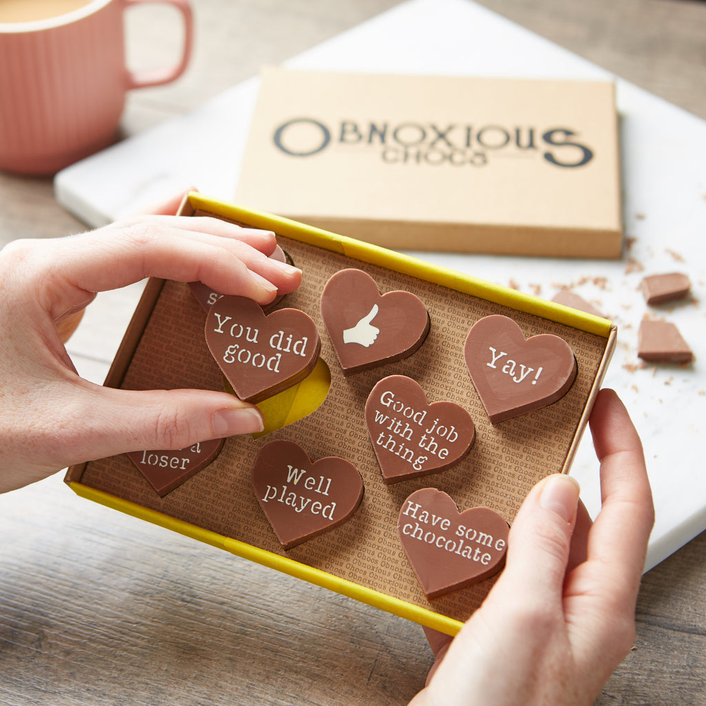 Hands holding a box of congratulations Obnoxious Chocs milk chocolate hearts