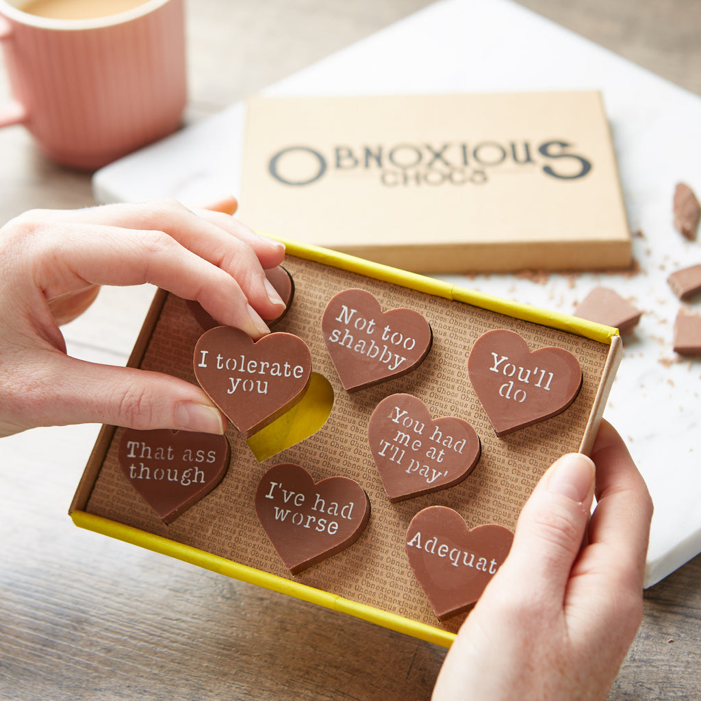 A selection of cheeky chocolate hearts for partners presented in a custom Obnoxious Chocs gift box.  This picture highlights a chocolate with an 'I tolerate you' message.