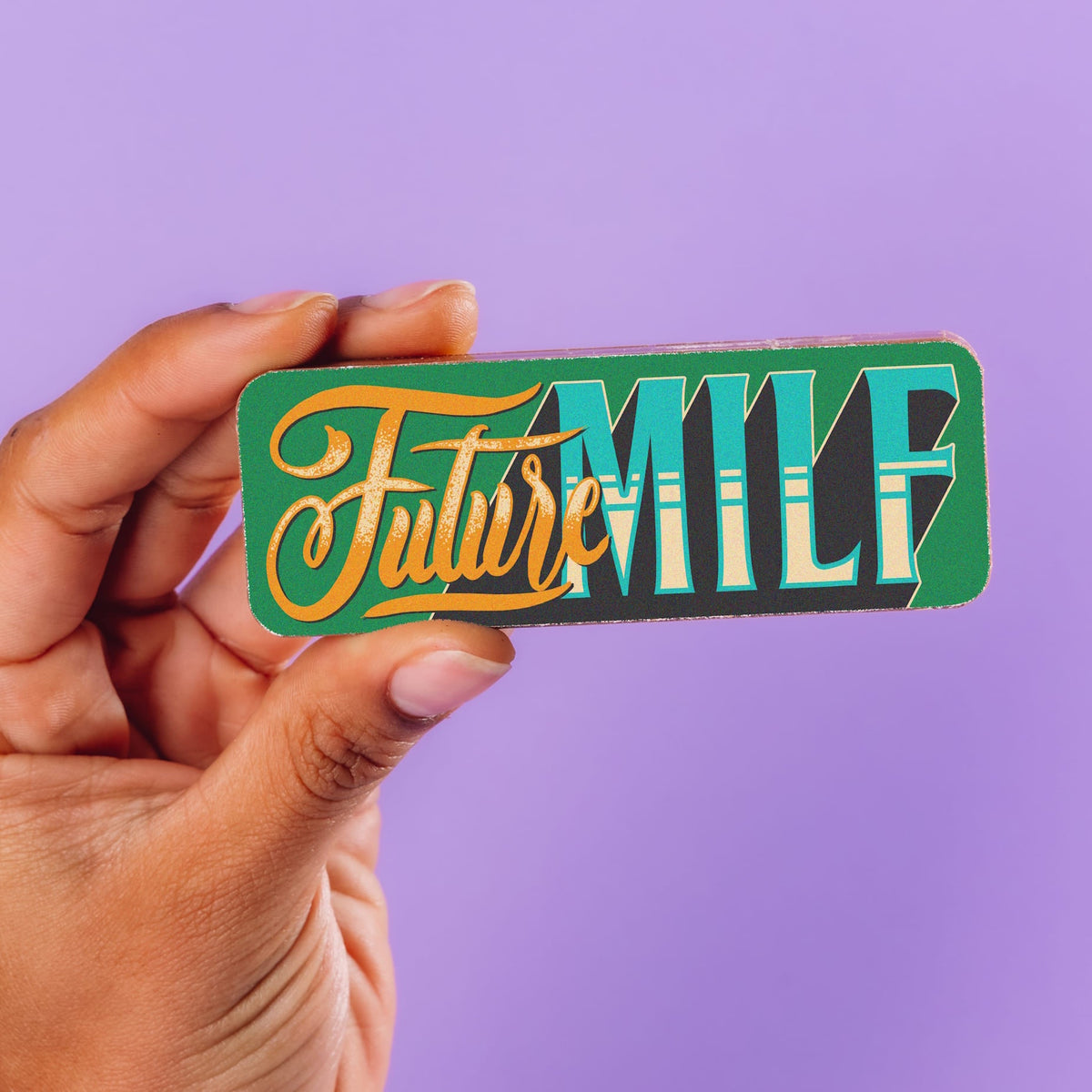 A chocolate bar decorated with a 'Future MILF' slogan in retro typography being held up.  Part of the Pregnancy Chocolate Selection Box.