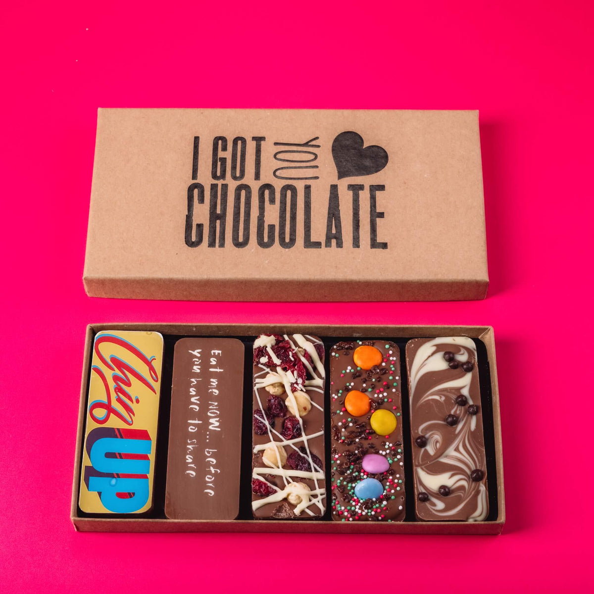 An open "I Got You Chocolate" gift box from Bagstock & Bumble, containing five handmade Belgian chocolate bars with delicious toppings and cheeky messages. Ideal as uplifting get well soon gifts after surgery.