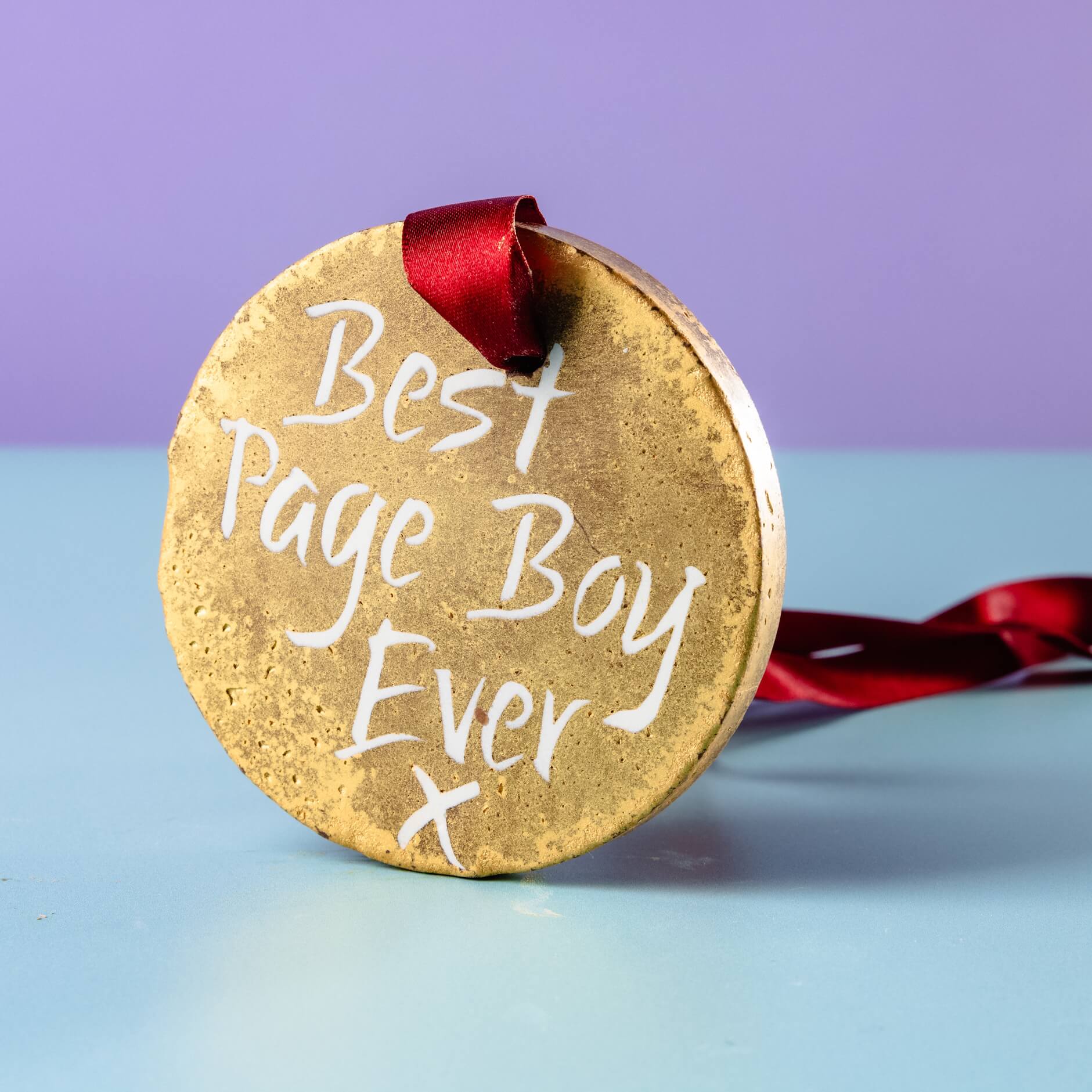 Gold chocolate medal with “Best Page Boy Ever” written on it, propped up with a red ribbon – a brilliant option for quirky and edible gifts for wedding party members.