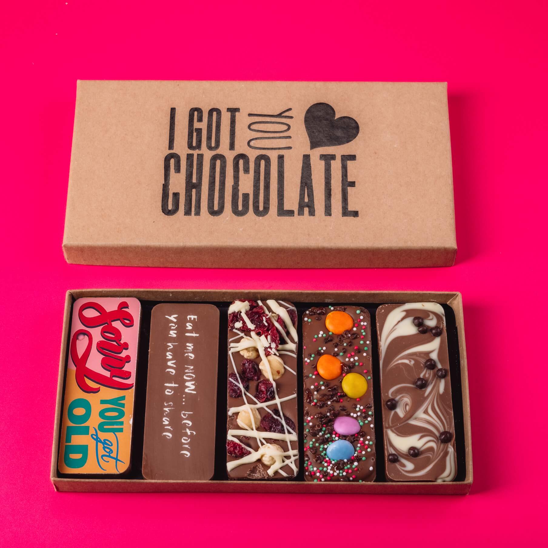 Open kraft gift box with an “I Got You Chocolate” motif containing five handmade chocolate bars.  Perfect as birthday gifts by post with a bit of personality.