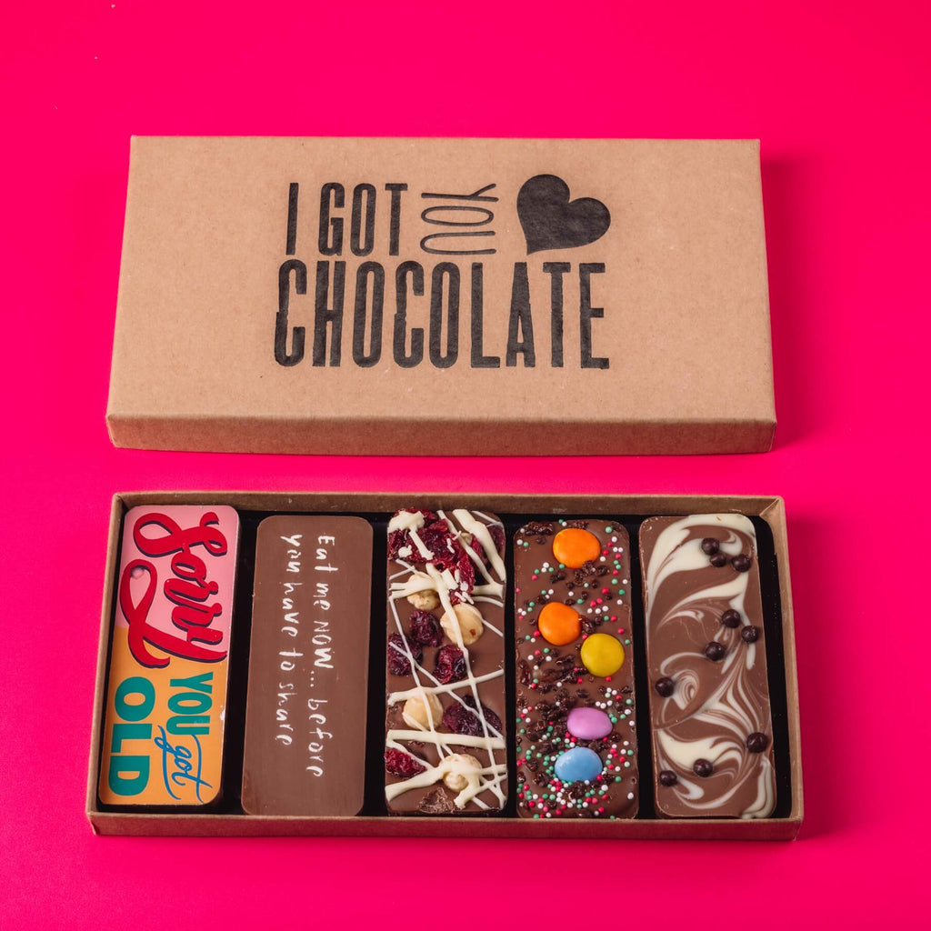 Open kraft gift box with an “I Got You Chocolate” motif containing five handmade chocolate bars.  Perfect as birthday gifts by post with a bit of personality.