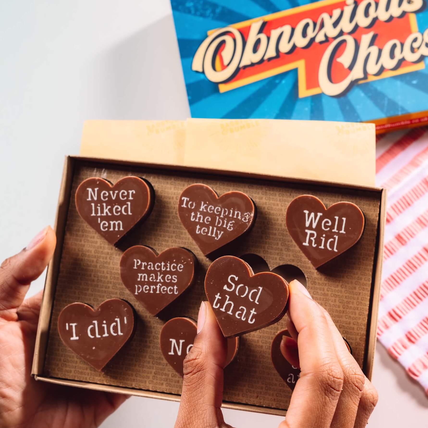 Funny Divorce or Break Up Gift - Hands holding a box of Bagstock & Bumble Divorce Obnoxious Chocs, packed with heart-shaped Fairtrade chocolates featuring cheeky messages.
