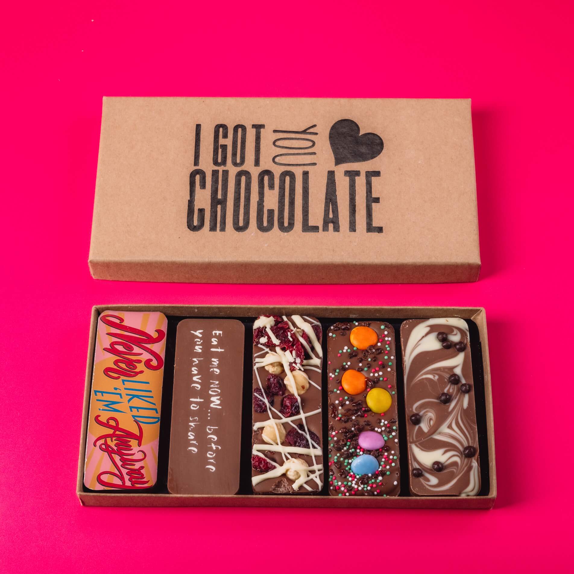 Open gift box with five quirky handmade chocolate bars with different flavours and messages., including “Never Liked ’Em Anyway” .  Our gift boxes make great new beginnings gift ideas.