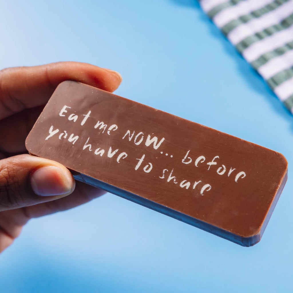 A chunky Belgian milk chocolate bar decorated with an 'Eat me now... before you have to share' message