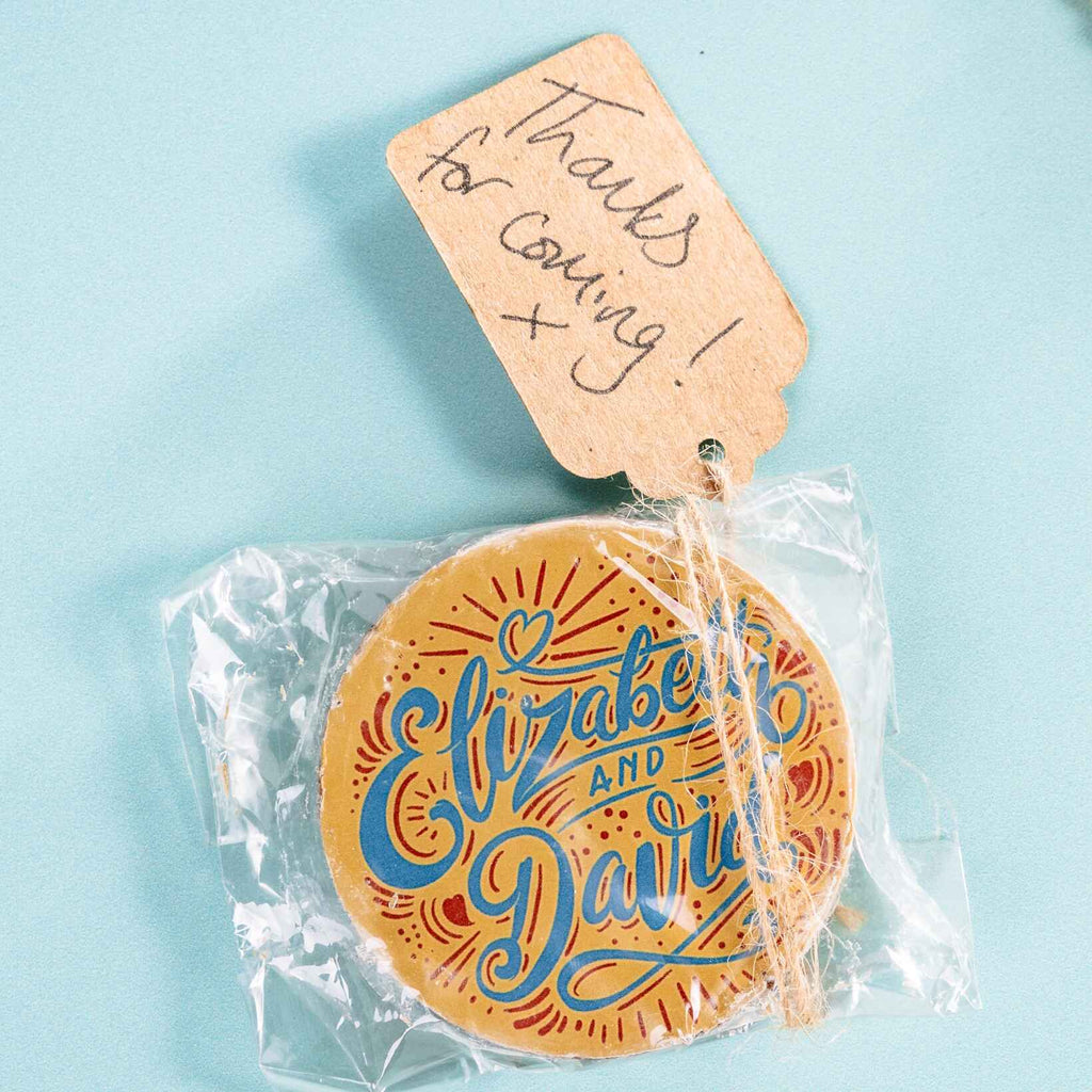 Round 'Elizabeth and David' personalised chocolate with a 'Thanks for coming' tag on a light blue background