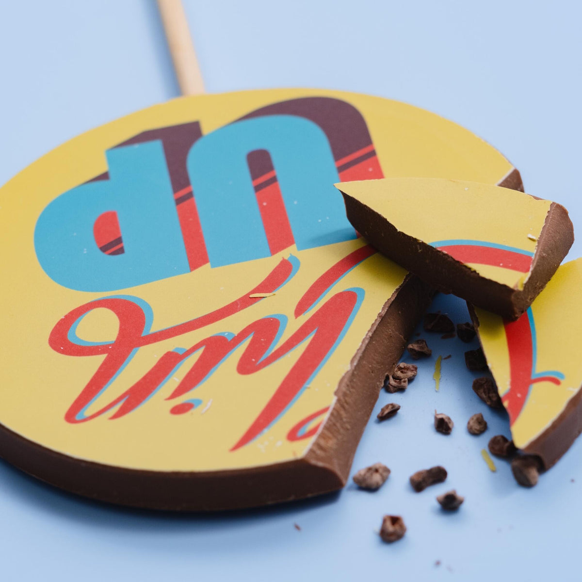 A close up of a giant chocolate picture lolly broken into pieces to reveal the chunky, solid milk chocolate centre