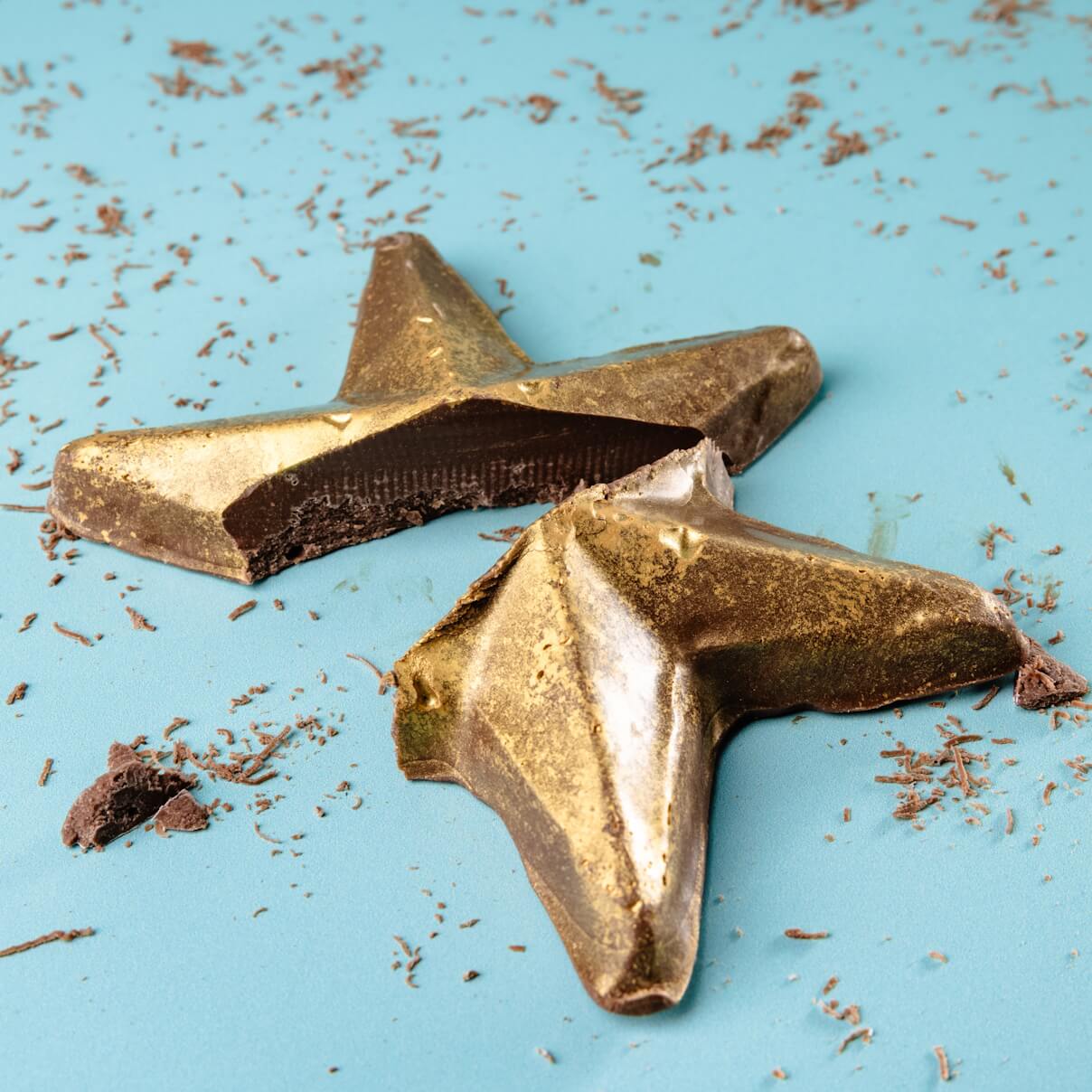 A broken chocolate star dusted with edible gold, surrounded by chocolate shavings – make proud of you gifts ideas that really make an impression.