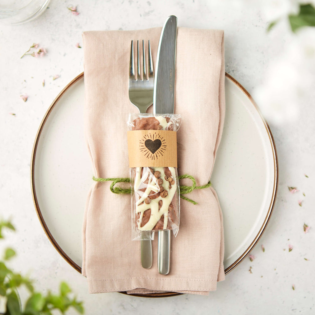 A honeycomb flavoured bar packaged with a heart motif shown on a wedding styled place setting