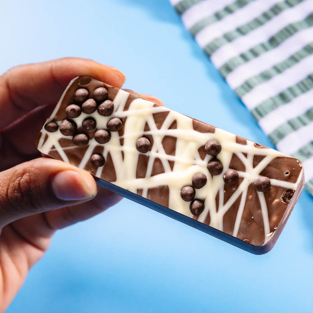 Scrumptious fairtrade milk chocolate bar full of honeycomb pieces and topped with crispy chocolate balls and white chocolate drizzle