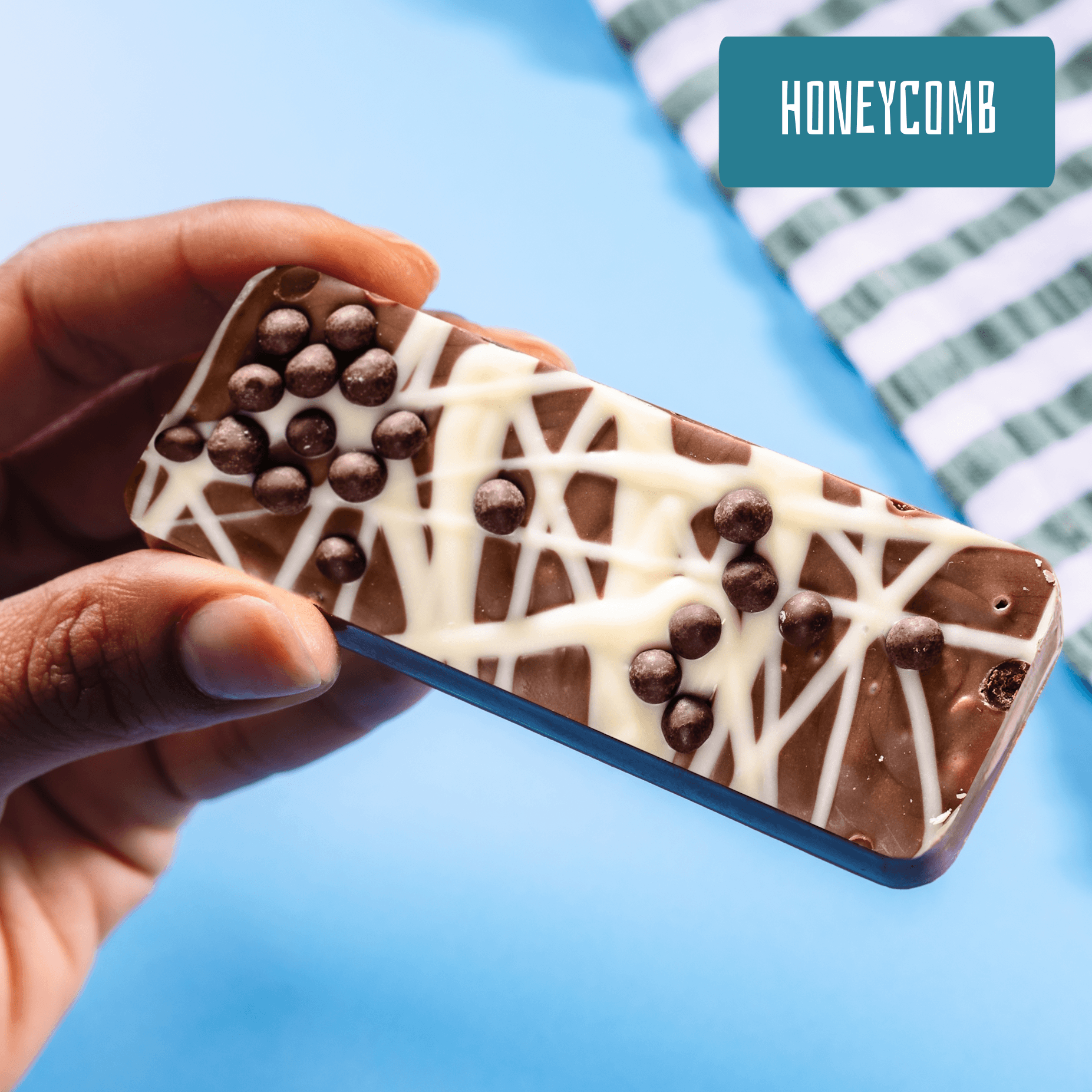 Scrumptious fairtrade milk chocolate bar full of honeycomb pieces and topped with crispy chocolate balls and white chocolate drizzle