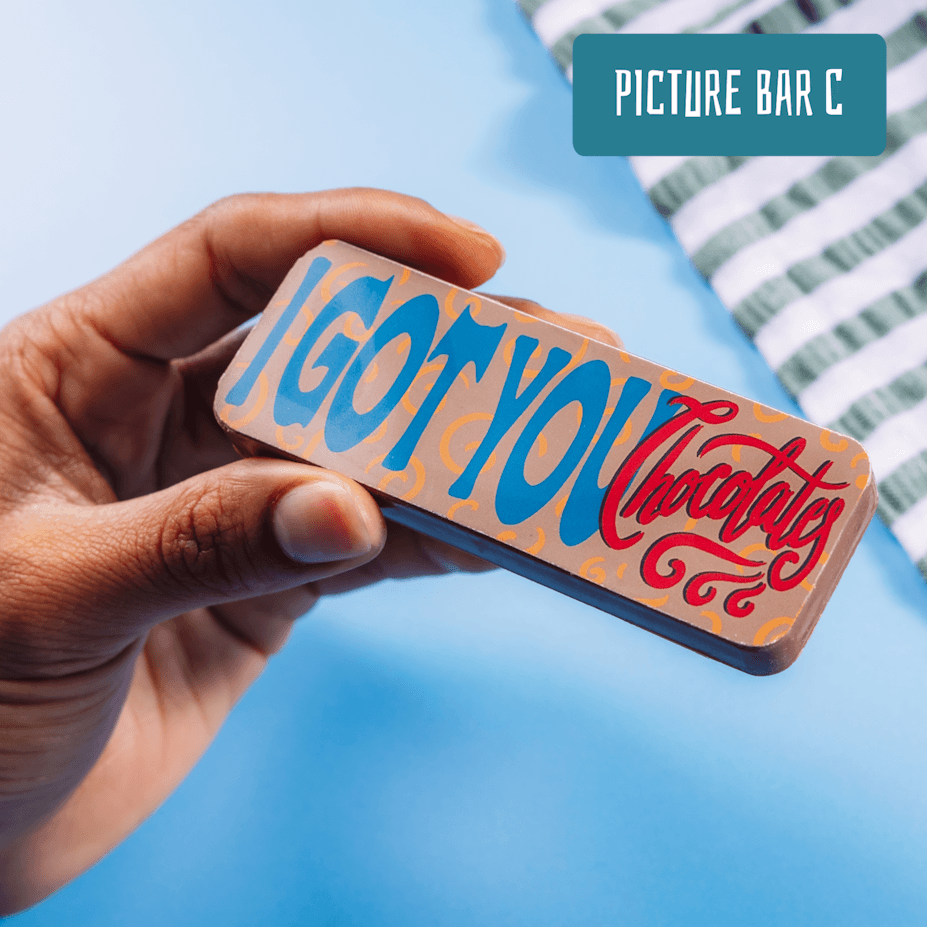 Close-up of a hand holding a chocolate bar that reads “I Got You Chocolate” – a light-hearted choice in gifts to say sorry to a friend.