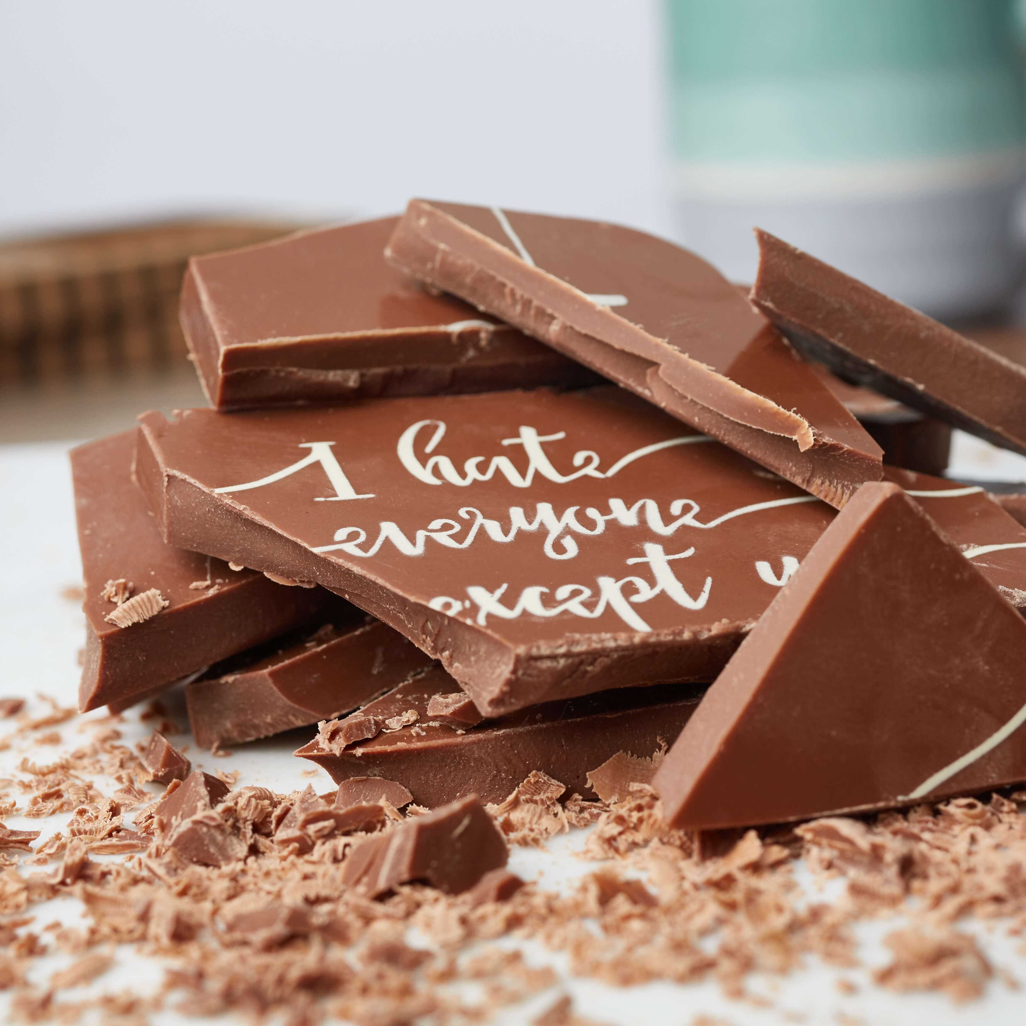Valentine's Chocolate - Close-up of broken Belgian chocolate bar showing the ‘I hate everyone except you’ message across the shards. 
 Equal parts cheeky and delicious.