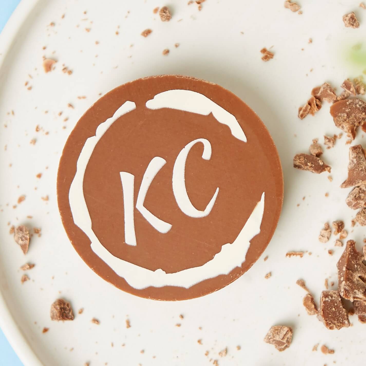 Sample corporate chocolate disc shown with a 'KC' logo displayed on the front