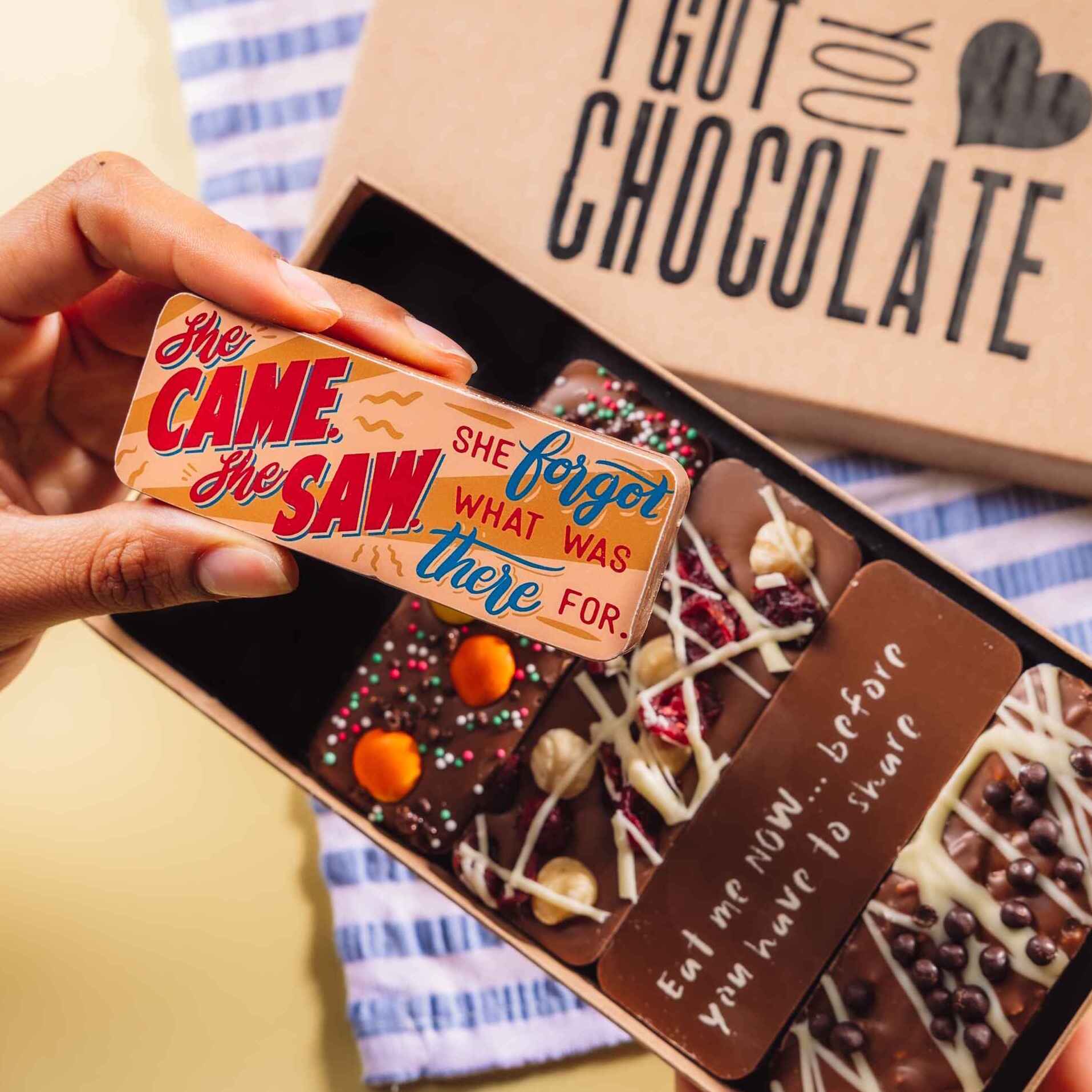A hand holding a cheeky chocolate bar that reads “She came, she saw, she forgot what she was there for”, presented in Bagstock & Bumble’s “I Got You Chocolate” box. An ideal gift for menopause with humour and high-quality chocolate