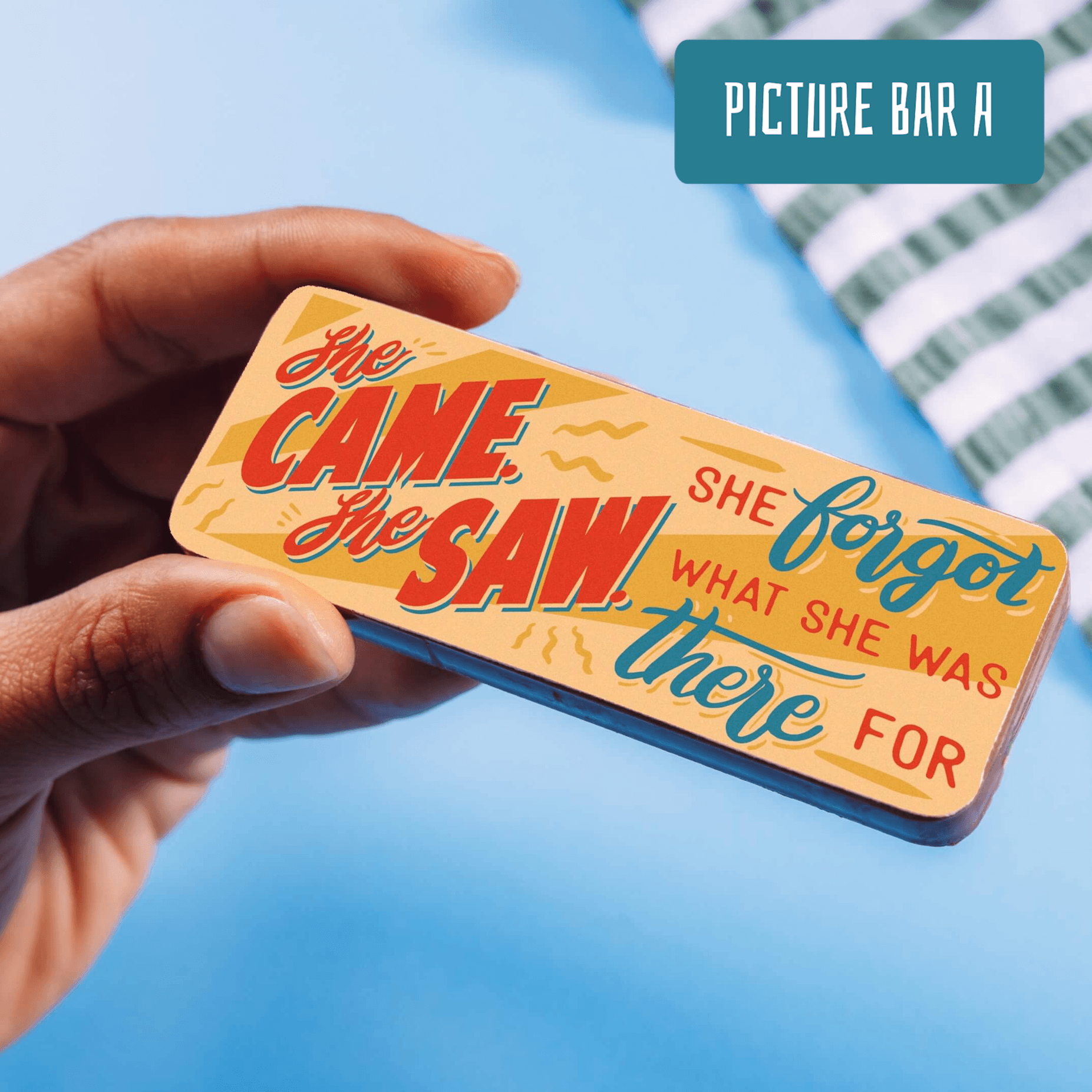 A hand holding a colourful chocolate bar with the slogan “She came, she saw, she forgot what she was there for.” From Bagstock & Bumble’s menopause gifts funny range.  Sweet, silly and deliciously relatable.