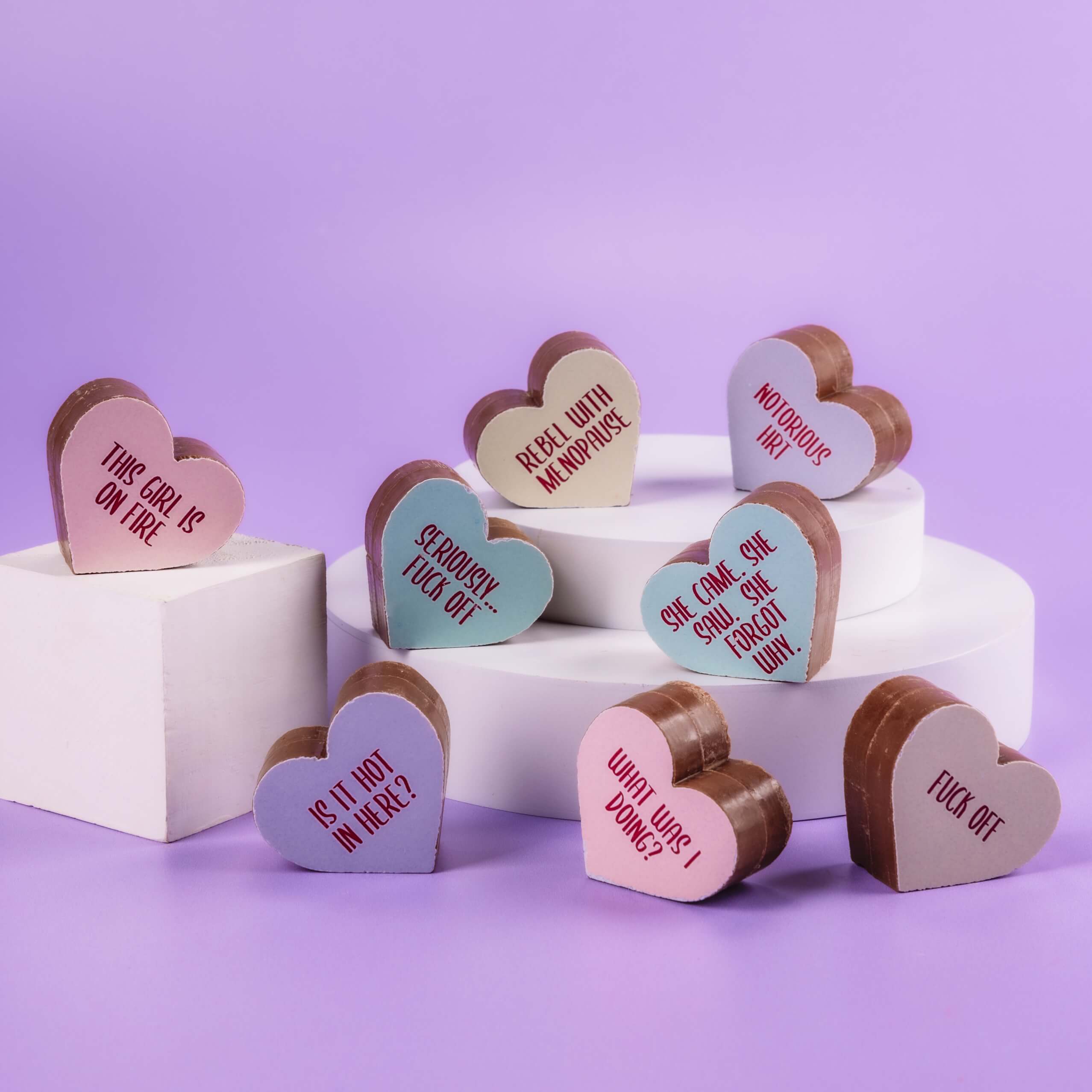 Perimenopause gift - A selection of Obnoxious Chocs from Bagstock & Bumble displayed on plinths, showing off cheeky messages like 'What was I doing?' and 'She came.  She saw.  She forgot why.'
