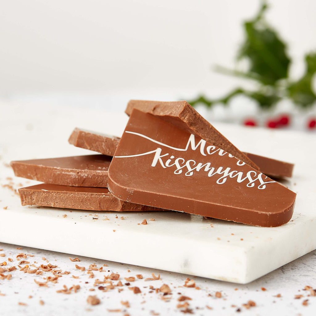 Chunks of broken milk chocolate with “Merry Kissmyass” visible across the surface – a no-nonsense choice for tongue in cheek funny secret Santa office gifts.