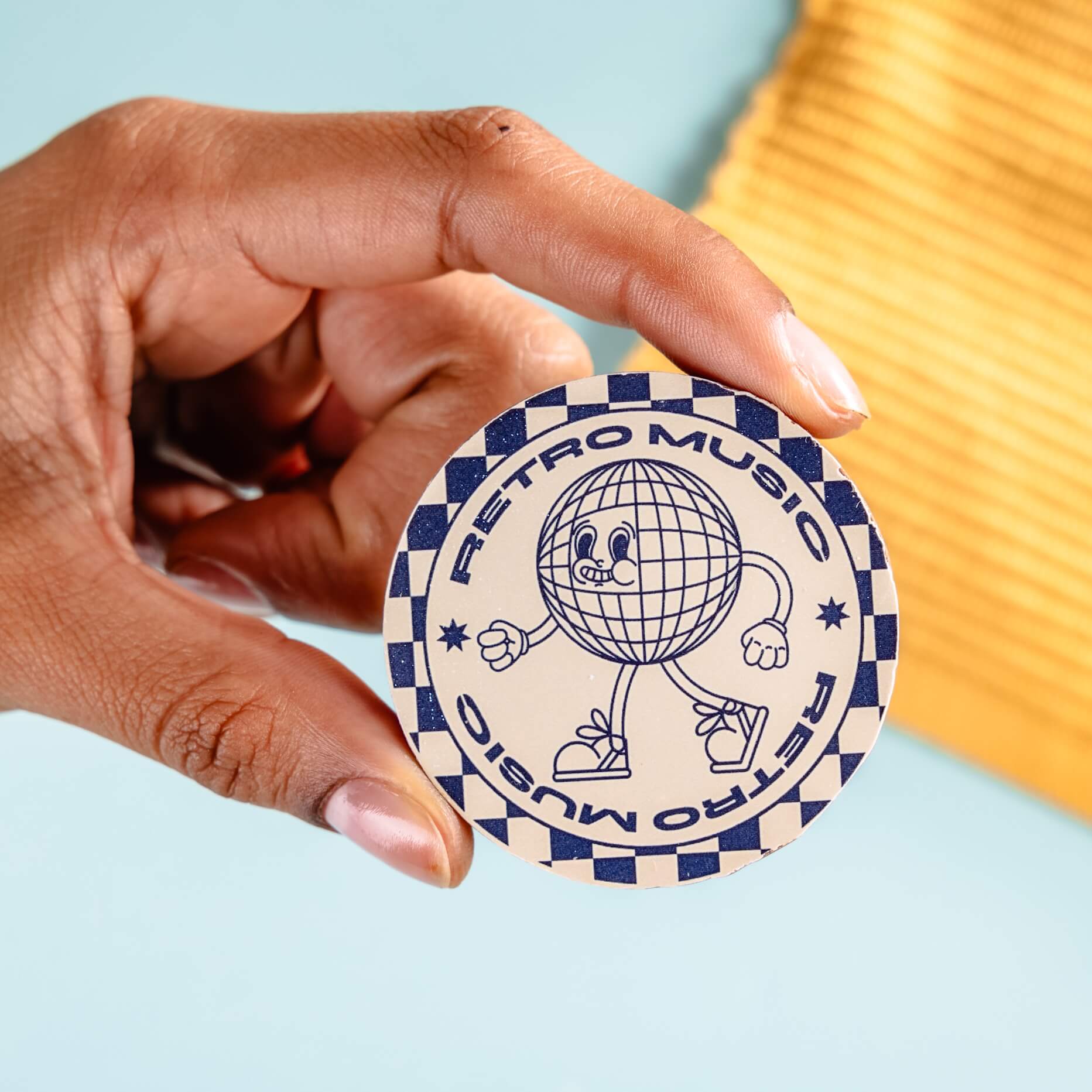 Hand holding a round chocolate with 'Retro Music' design on a light blue background