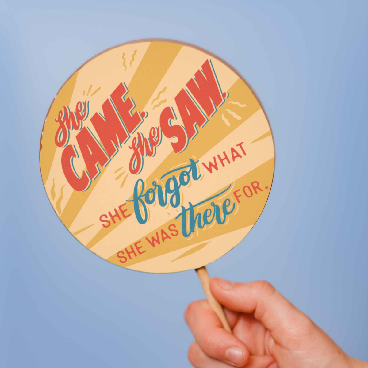 A ‘She came, she saw’ chocolate lolly being held up over a light blue background.  These delicious, handmade, fairtrade chocolate lollies make ideal funny gifts for ladies approaching the menopause.