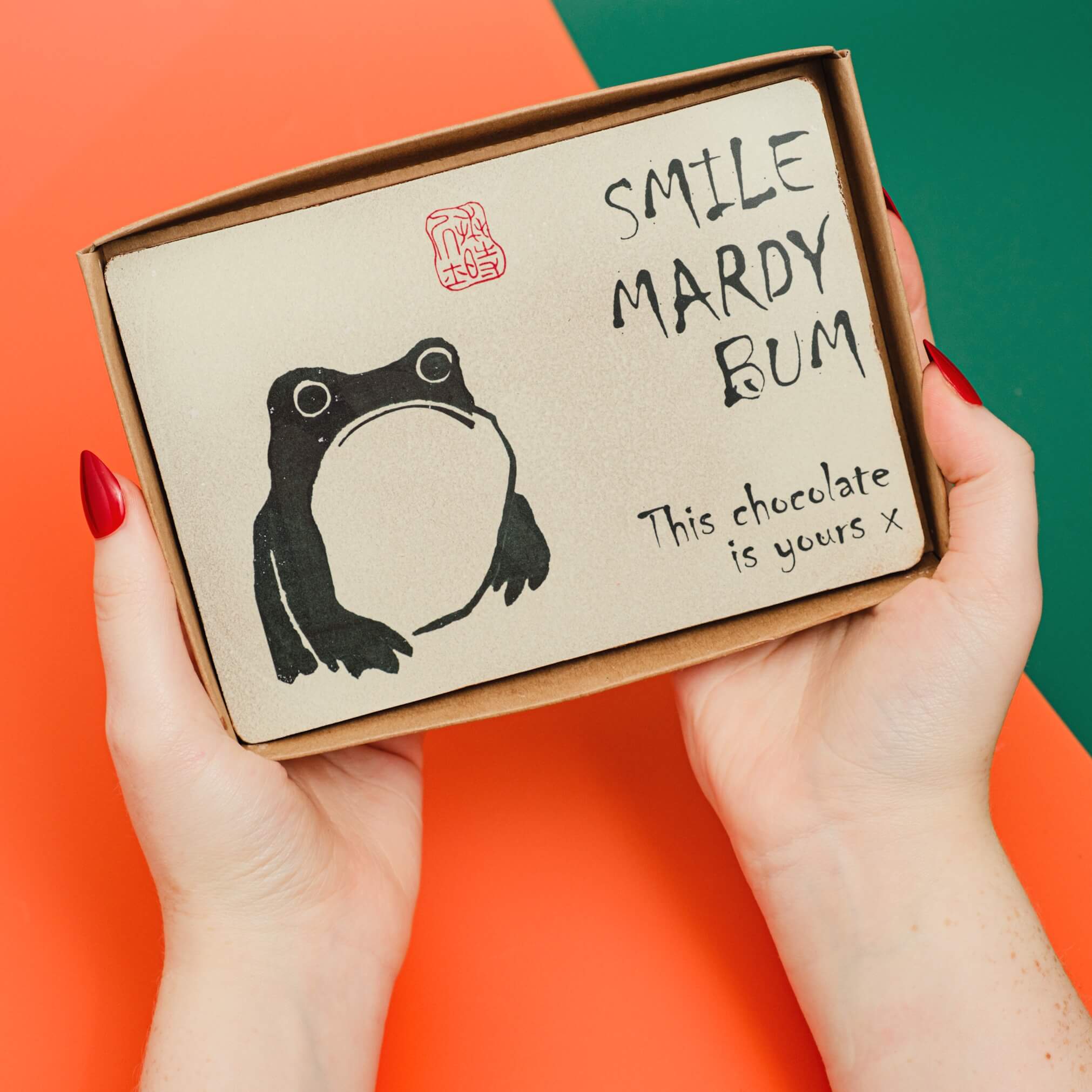 Obnoxious Chocs boxed Easter treat with edible image of a moddy frog and a “Smile Mardy Bum” tongue-in-cheek message.