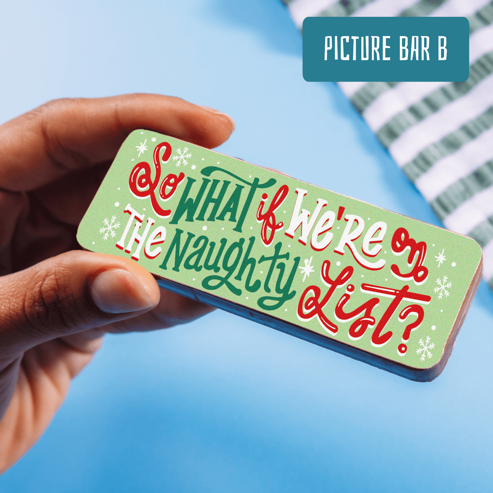 Hand holding up a colourful chocolate bar that reads "So what if we're on the naughty list?" in festive red, green and white lettering.