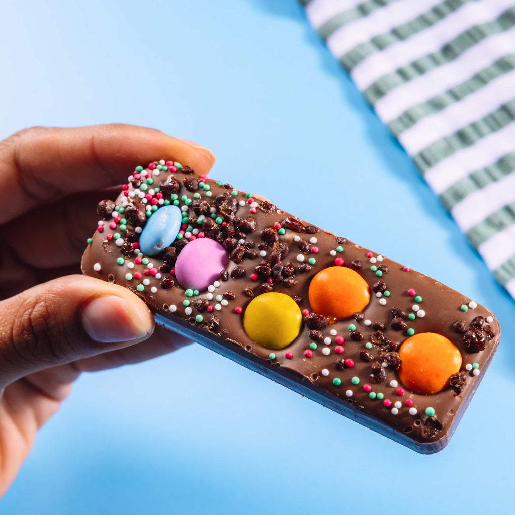 Chunky fairtrade milk chocolate bar topped with chocolate beans, sprinkles and popping candy