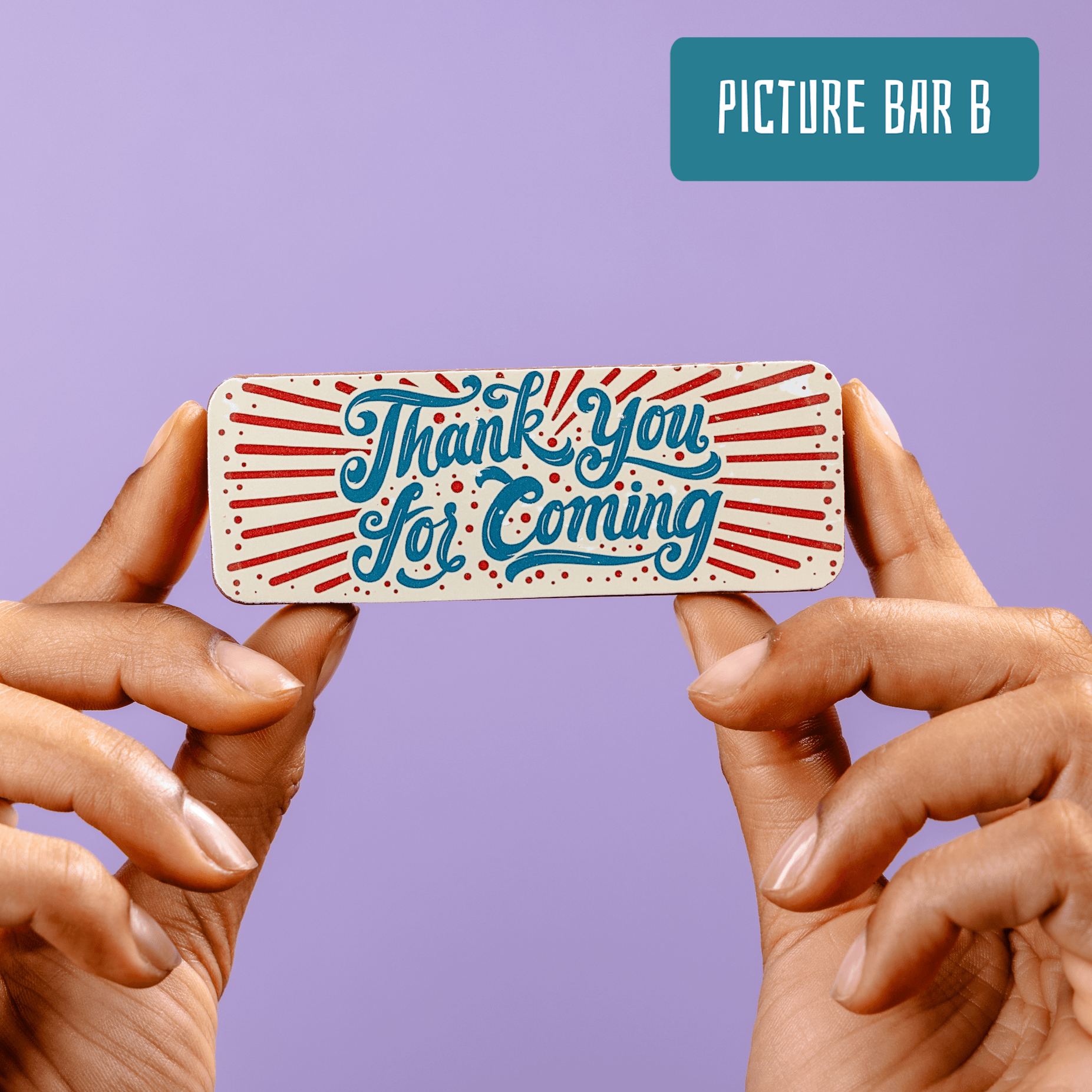 A small, colourful chocolate bar being held up by two hands.  The bar has a colourful red, white and blue vintage style 'Thank you for coming' edible message on the front.