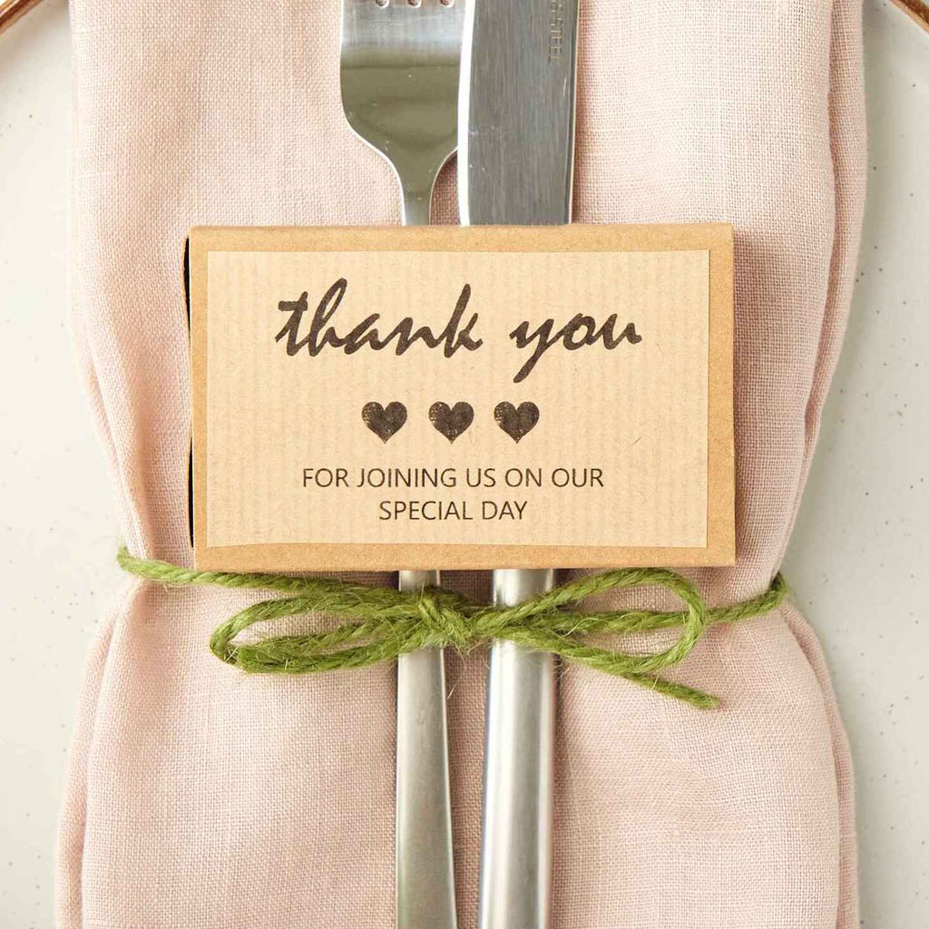 Gift box with a 'thank you for joining us on our special day' message on a wedding table place setting.