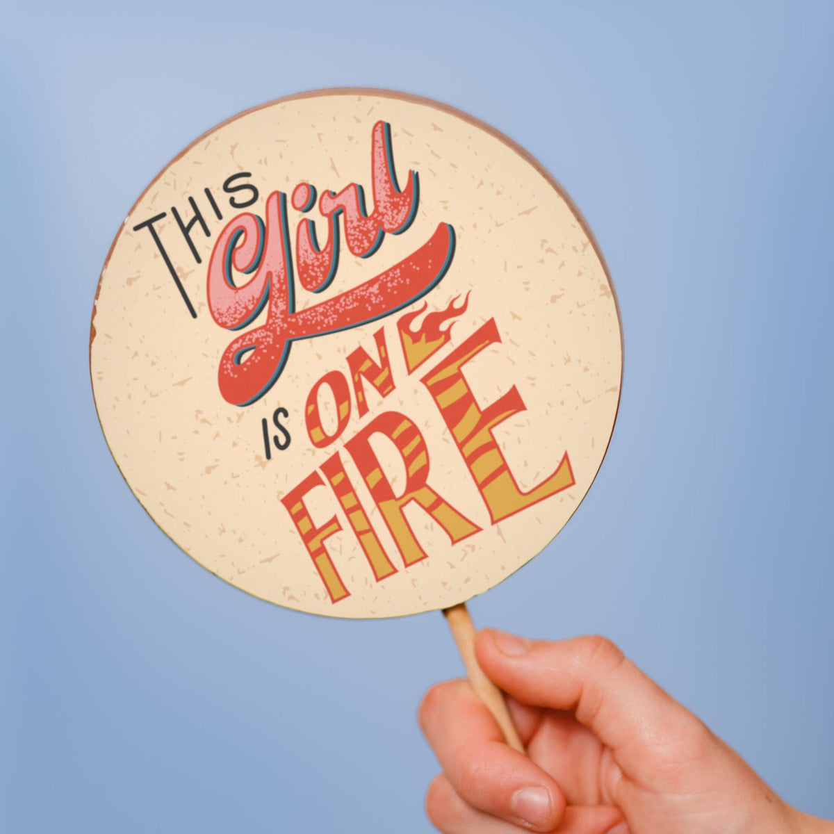 A close up of the main body of the ‘This girl is on fire’ handmade, Belgian chocolate lollipop being held in front of a light blue background