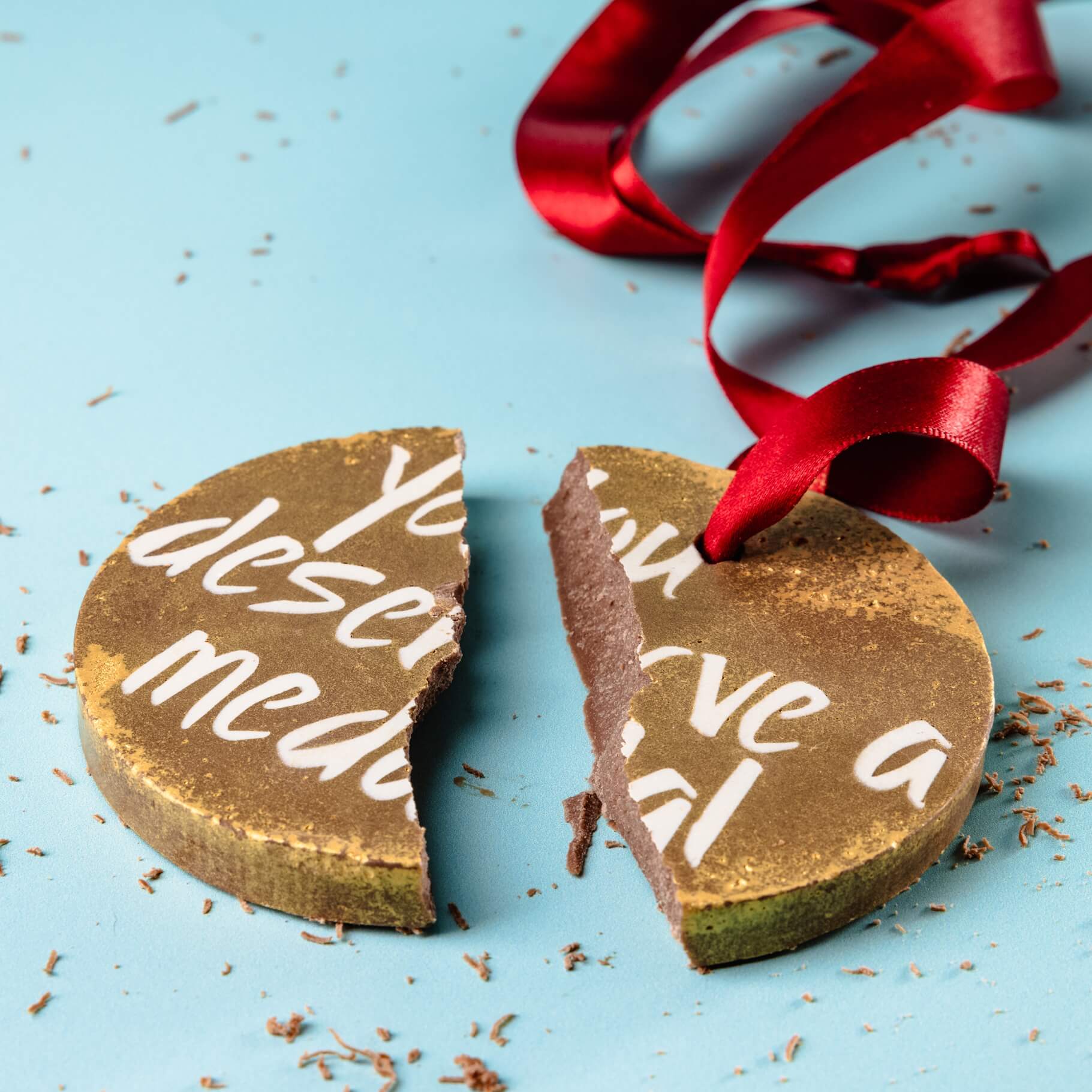 Smooth Belgian chocolate medal – A rich and creamy Belgian milk chocolate medal, broken into pieces to reveal its high-quality, Fairtrade chocolate goodness.