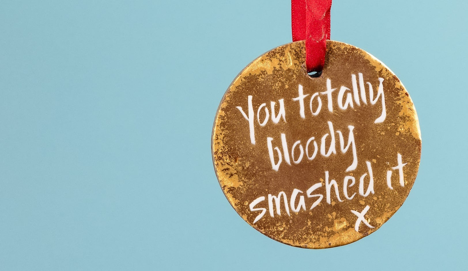 A shiny chocolate medal being held up by its red ribbon. A yummy gift to congratulate your friend on their new job. 