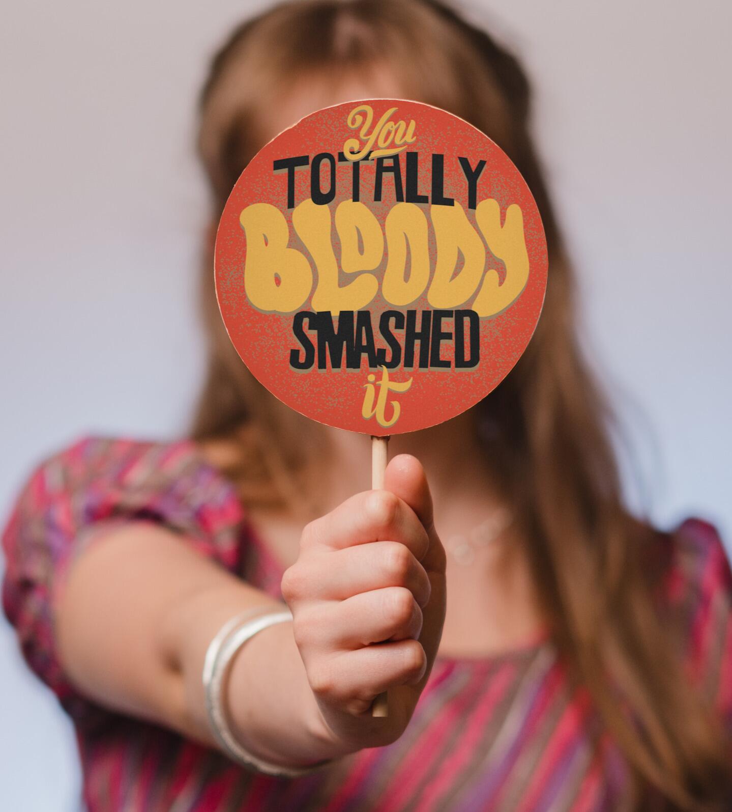A jumbo congratulations chocolate lolly with a colourful 'You totally bloody smashed it' message being held up to the camera.