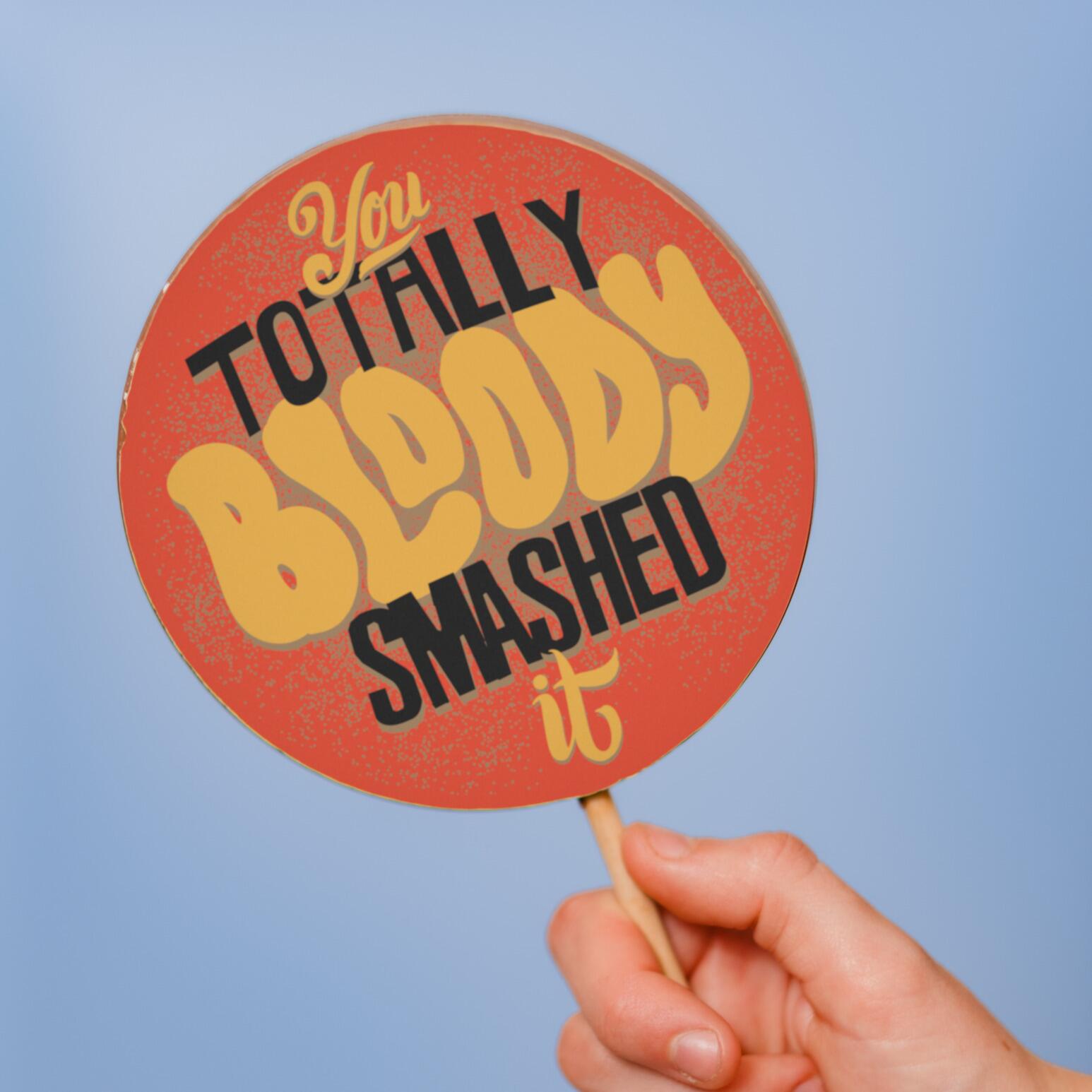 A hand holding up our fairtrade chocolate congratulations lolly to showcase it's jumbo size - 13cm diameter