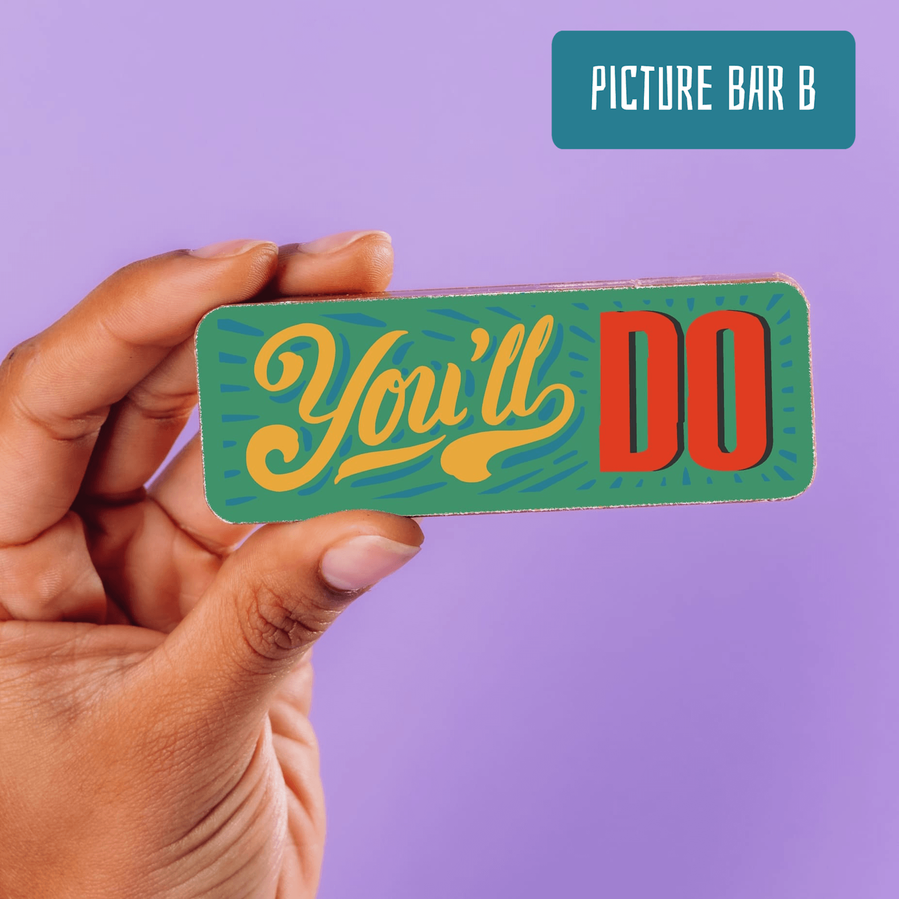 A hand holding a mini chocolate bar that says “You’ll Do” in bold, colourful text – the kind of realistic romance that makes the perfect gift for committed couples.