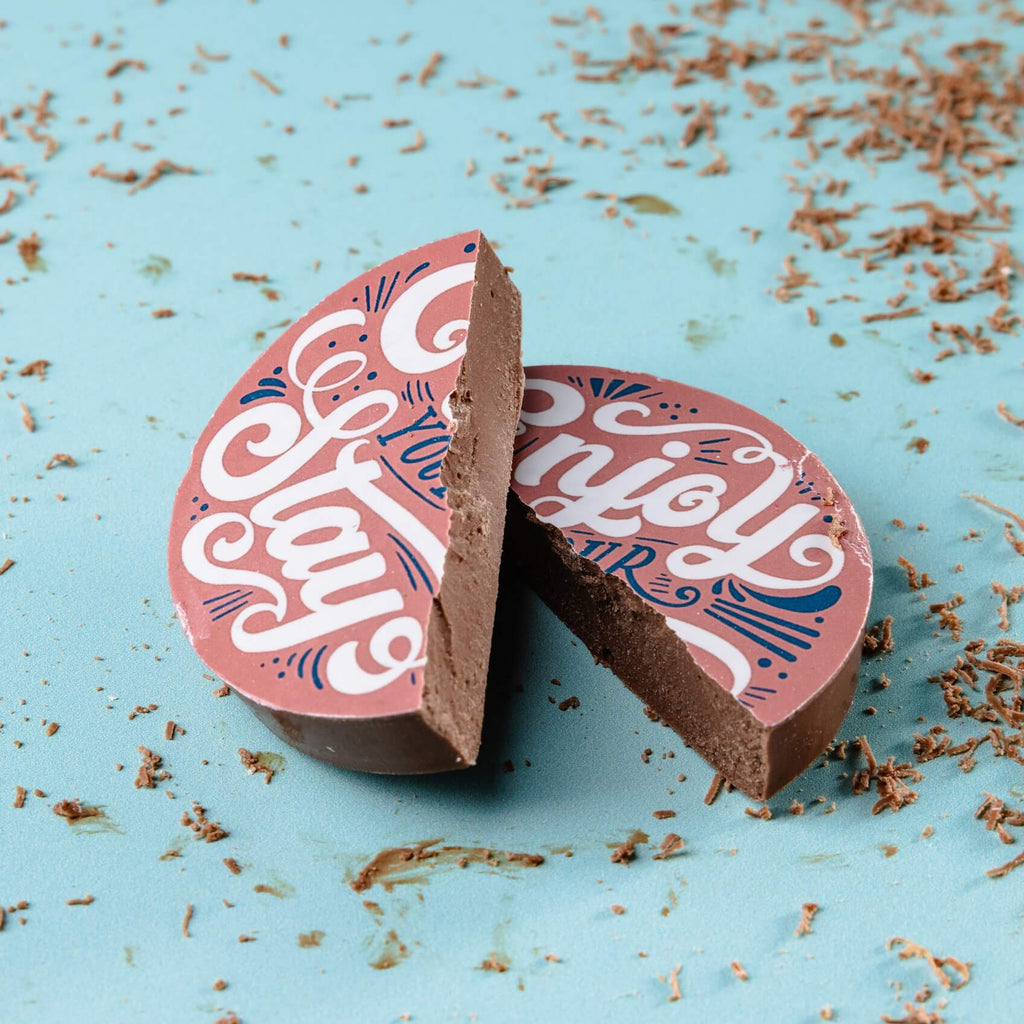 Chocolate disc with pink blue and white 'Enjoy your stay' design on a blue background