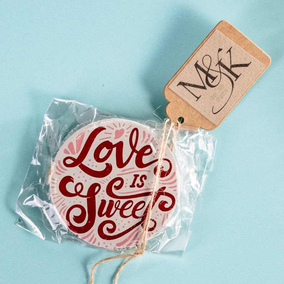 Round chocolate with 'Love is Sweet' text in a clear bag with a tag personalised with the initials M & K