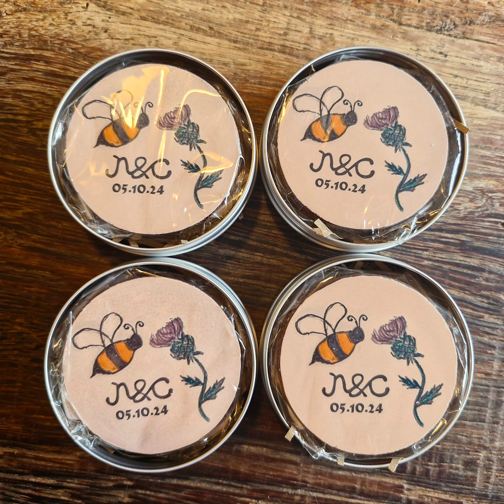 Four round chocolates with bee and flower design on a wooden surface