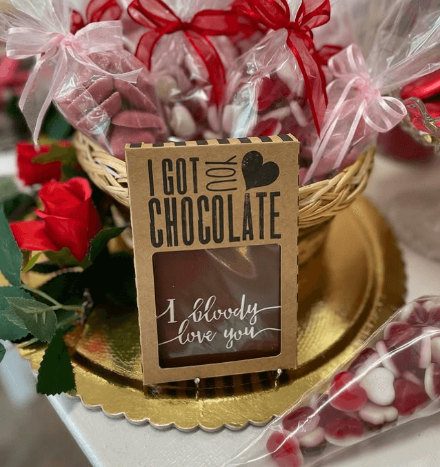 Chocolate bar in an 'I got you chocolate' box with an 'I bloody love you' message, surrounded by flowers and sweets.