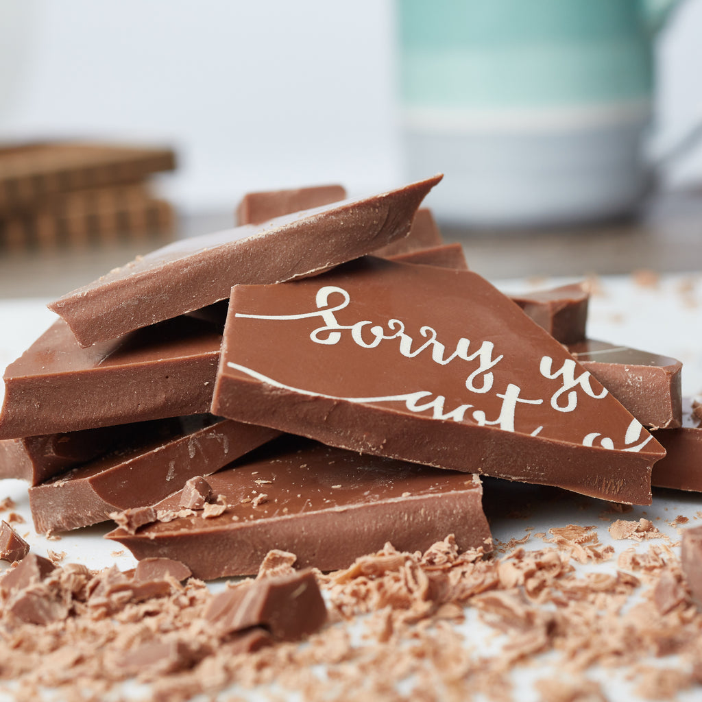 Chunks of the 'Sorry you got old' chocolate bar piled up to show the solid milk chocolate centre