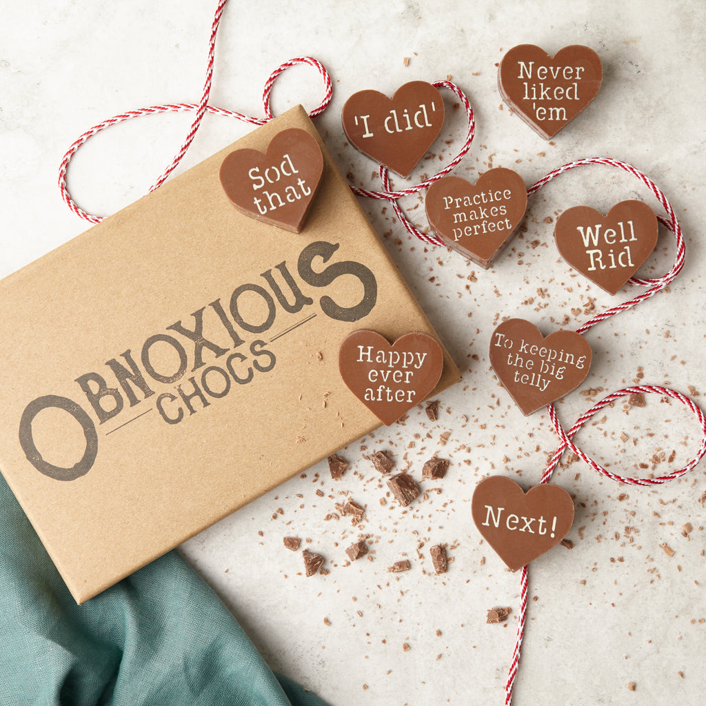 An overhead view showing the eight chocolate hearts in the divorce Obnoxious Chocs box. The slogans on each are 'Sod that', 'I did', 'Never liked 'em', 'Practice makes perfect', 'Well rid', 'Happy ever after', 'I'm keeping the big telly' and 'Next!'